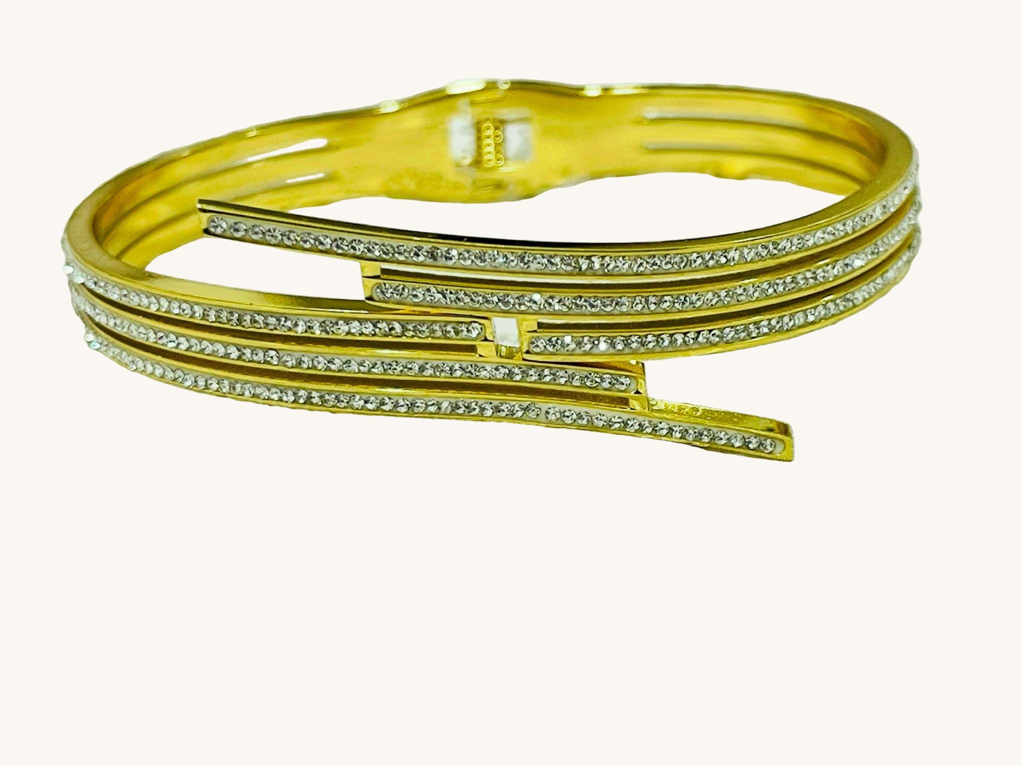 Sleek triple lines gold bracelet with sparkling stones and modern minimalist design on textured fabric background
