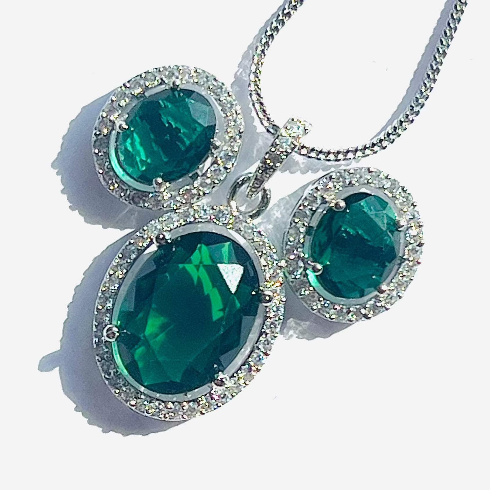 Emerald grand pendant set with oval green stones and silver chain surrounded by white diamonds