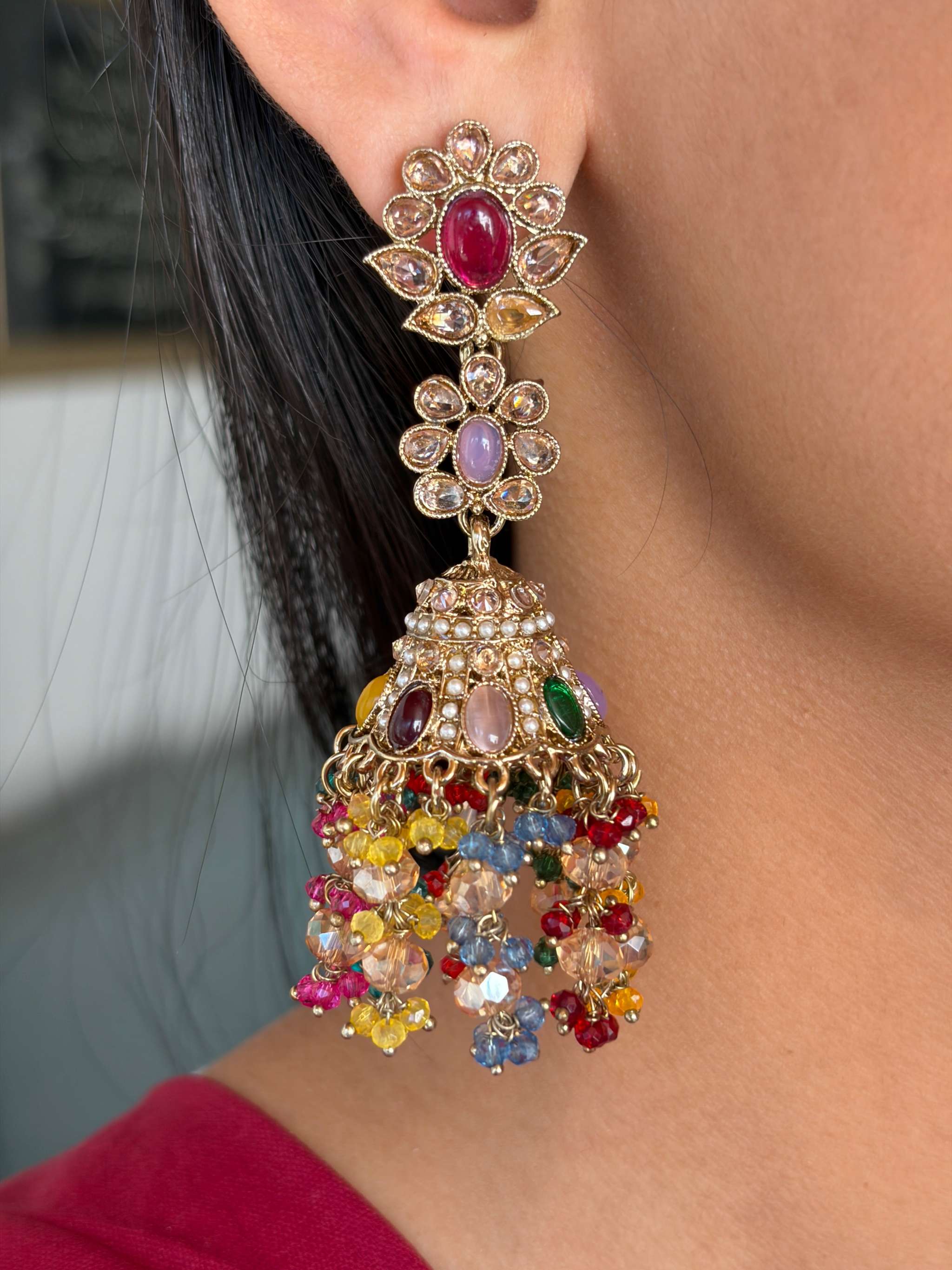 Close-up of a vibrant Satrangi Jhilmil Bahaar Jhumka earring with multicoloured stones and intricate gold detailing.