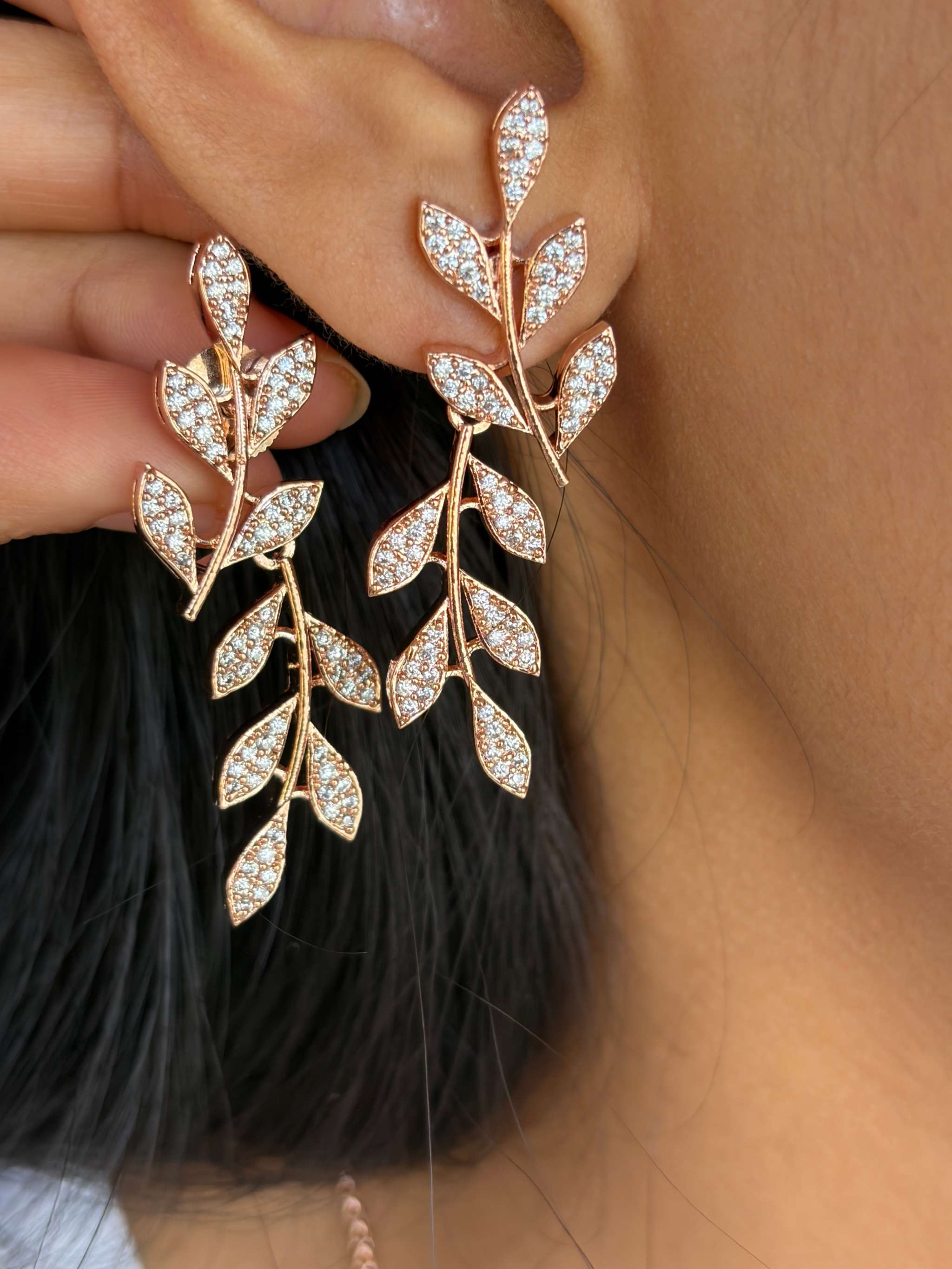 close-up of rosegold leafy embrace necklace set earrings with sparkling crystals on woman
