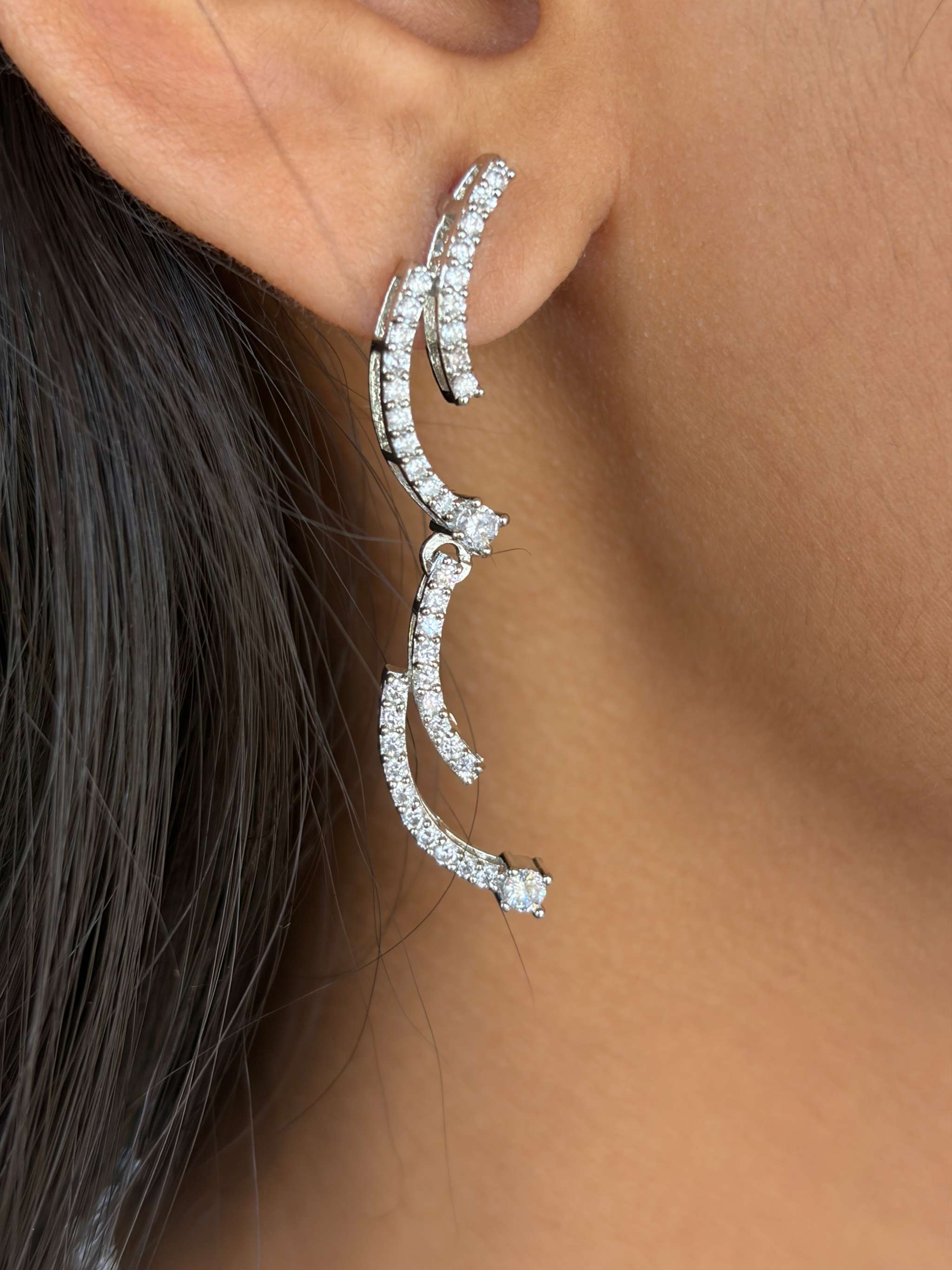 Close-up of a silver crescent silhouette necklace set earring adorned with sparkling stones