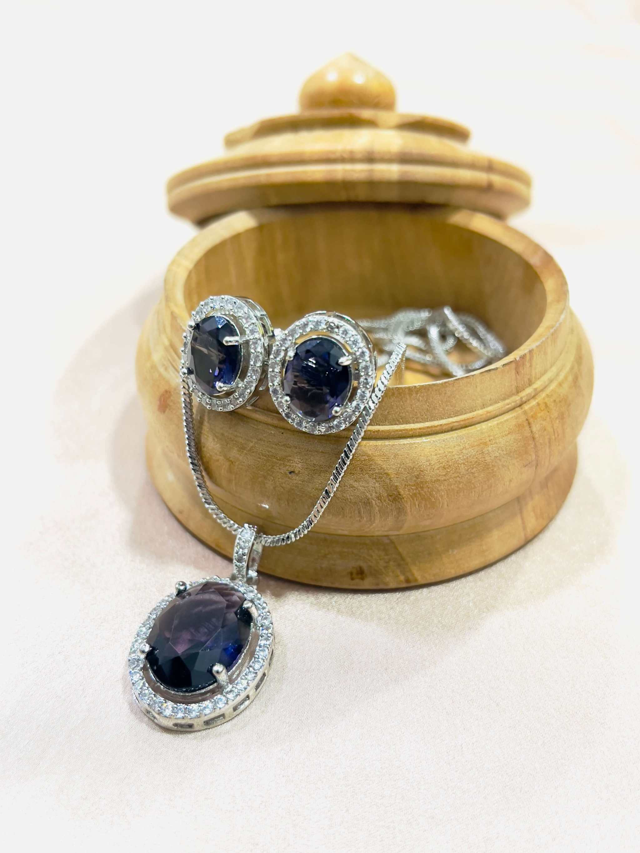 Indigo Grand Pendant Set with oval indigo stones surrounded by small white diamonds displayed in a wooden box