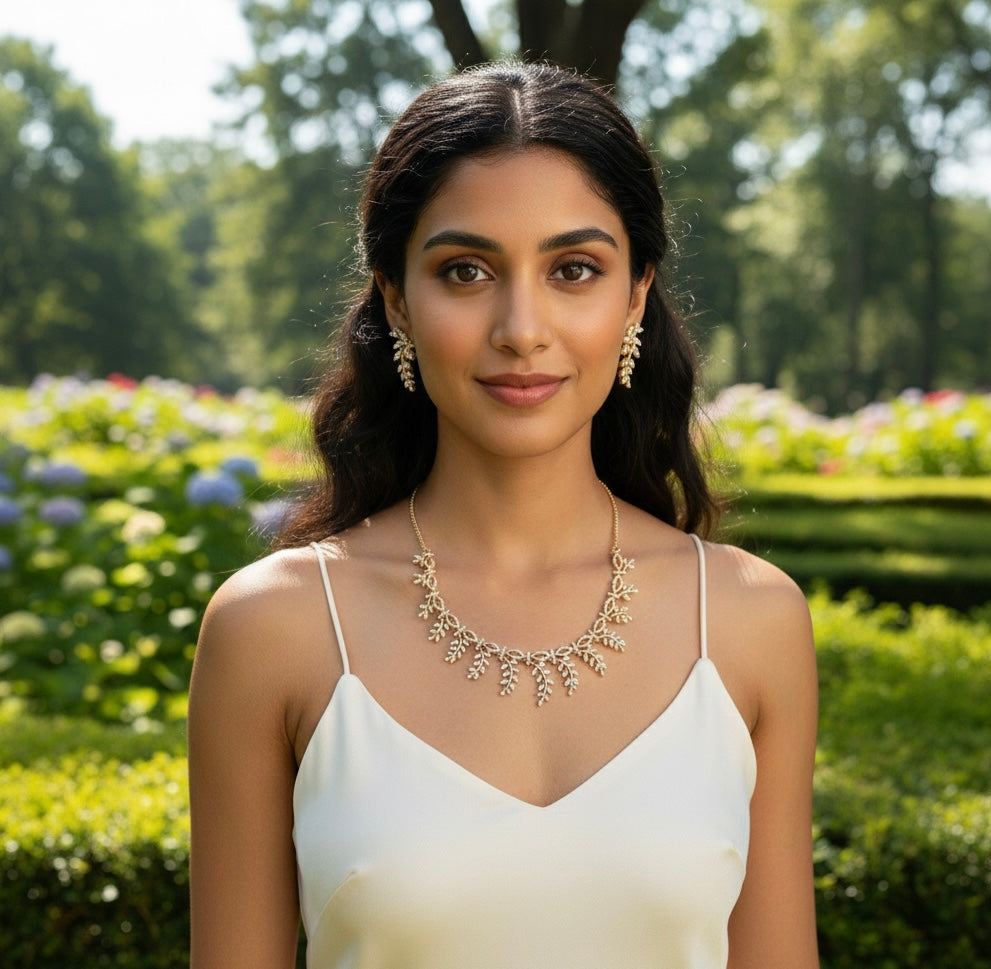 Woman wearing Everglow Willow Necklace Set in gold with matching earrings in outdoor garden setting