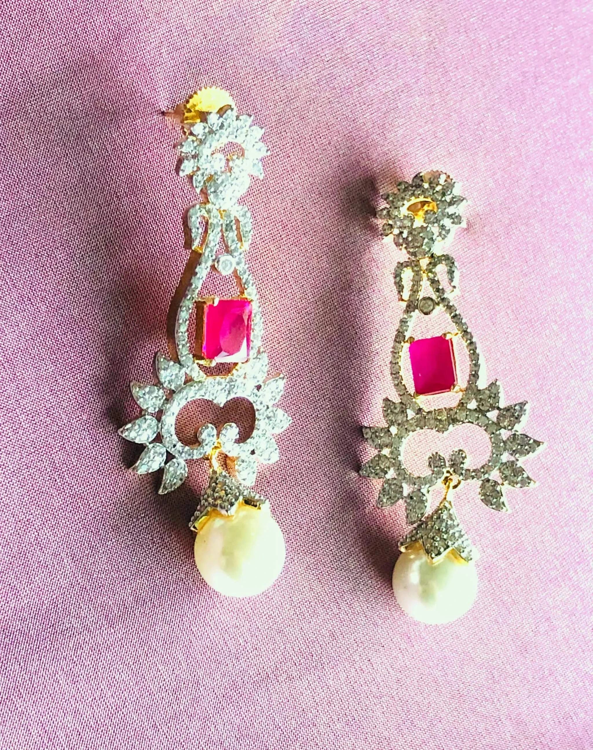 Silver white and red ruby dangler earrings with pearl drops on pink background