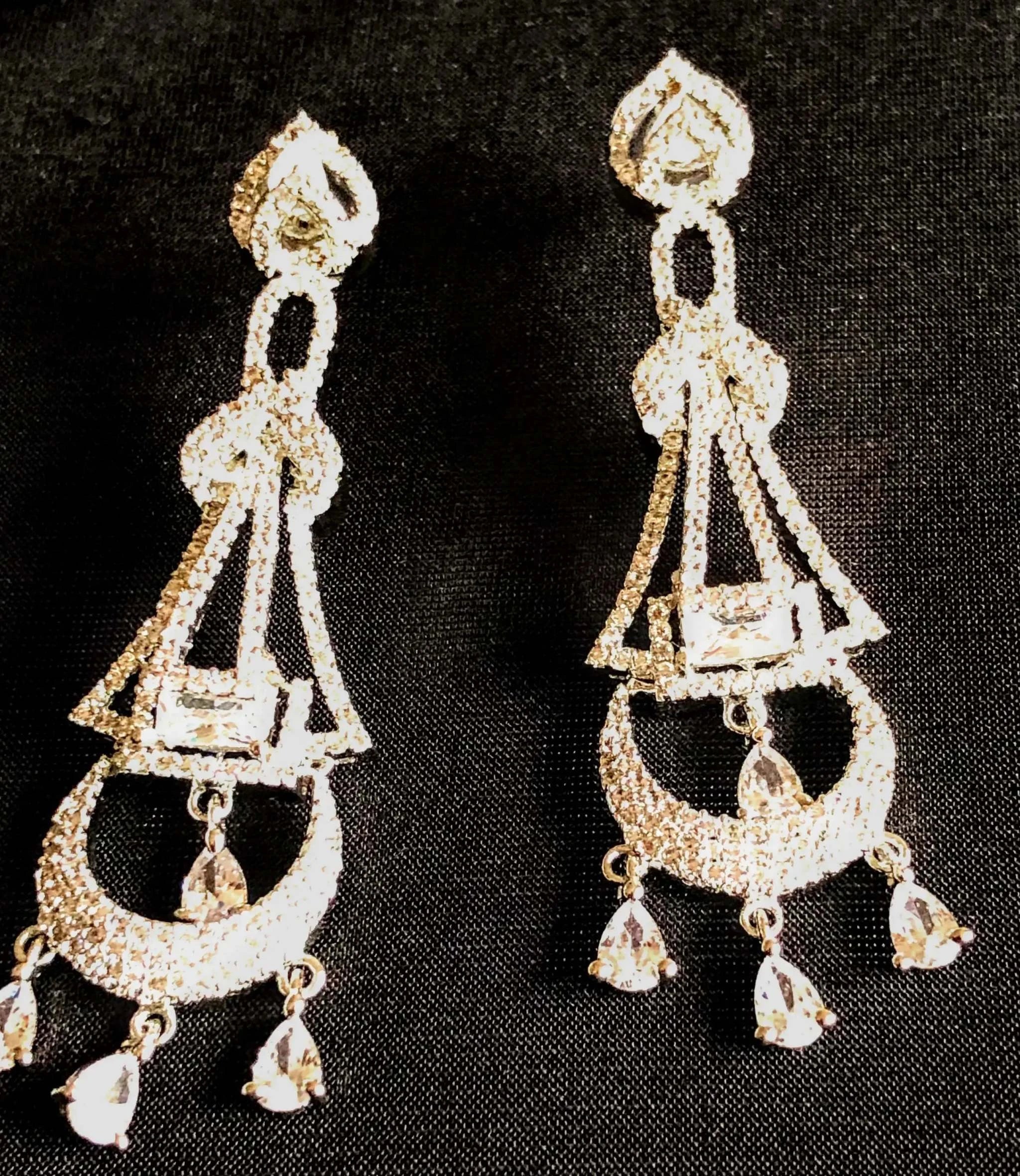Silver and white diamond dangling earrings with intricate geometric design and teardrop accents