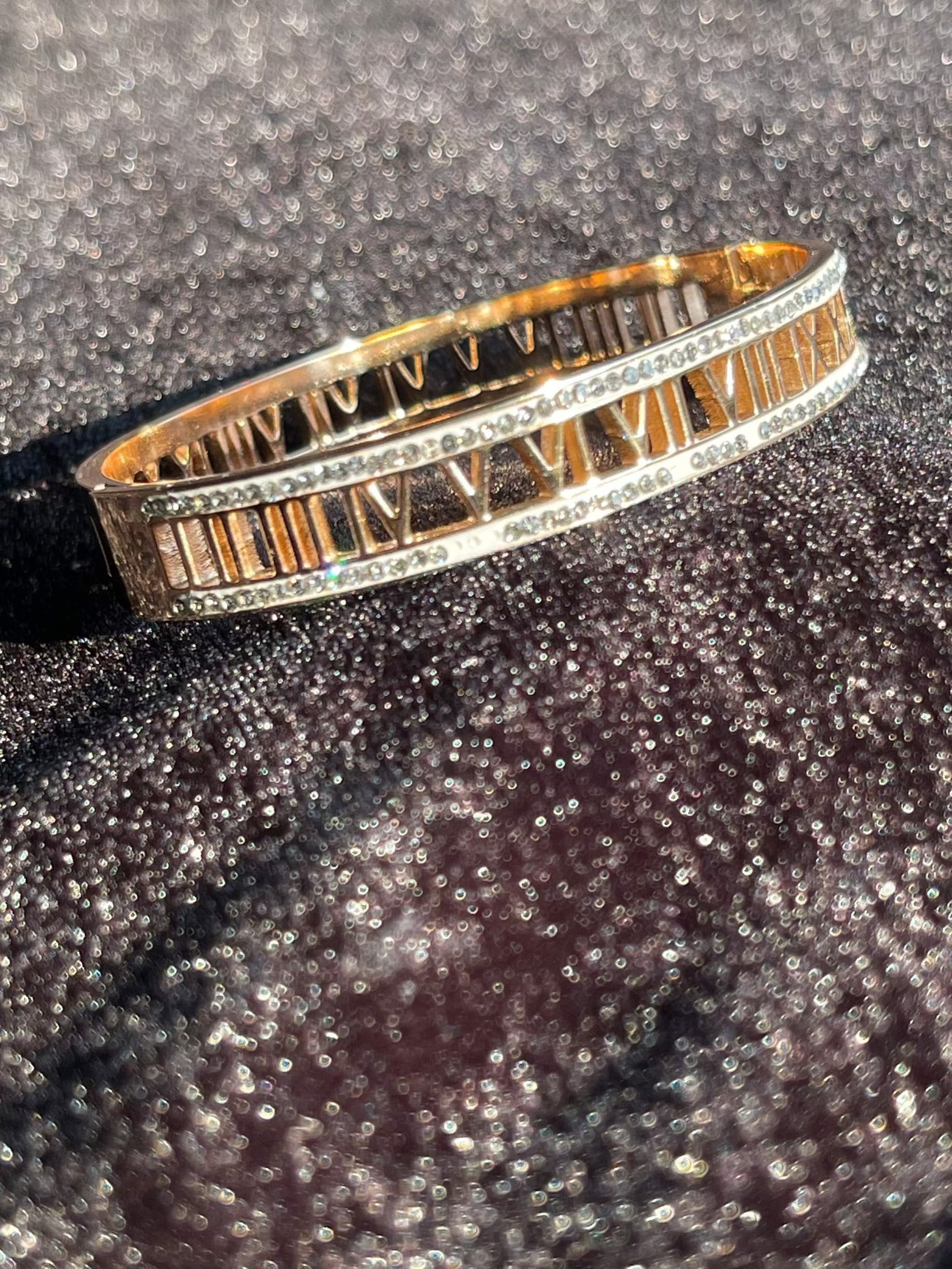 Rose gold bracelet featuring engraved Roman numerals and sparkling accents on a glittery surface