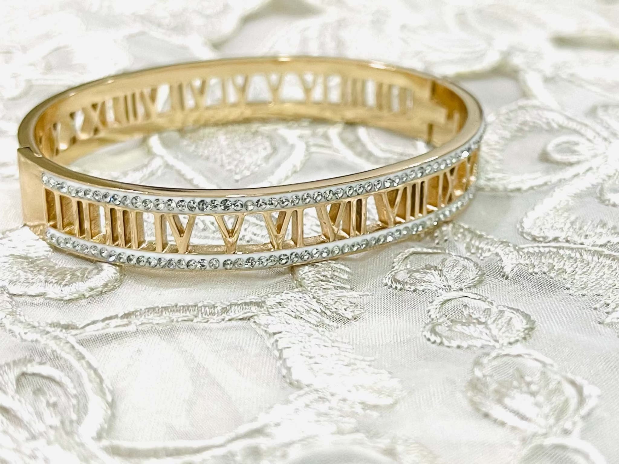 Rose gold bracelet with Roman numerals and rhinestone accents on lace background