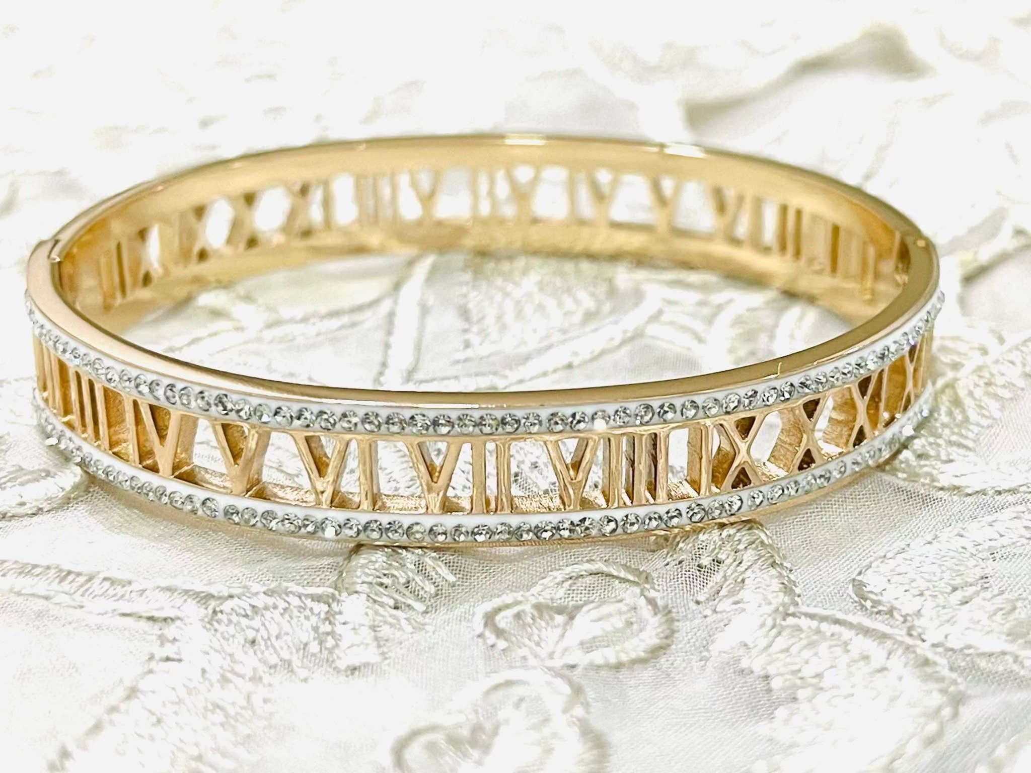 Rose gold bracelet with engraved Roman numerals and crystal accents on a delicate band