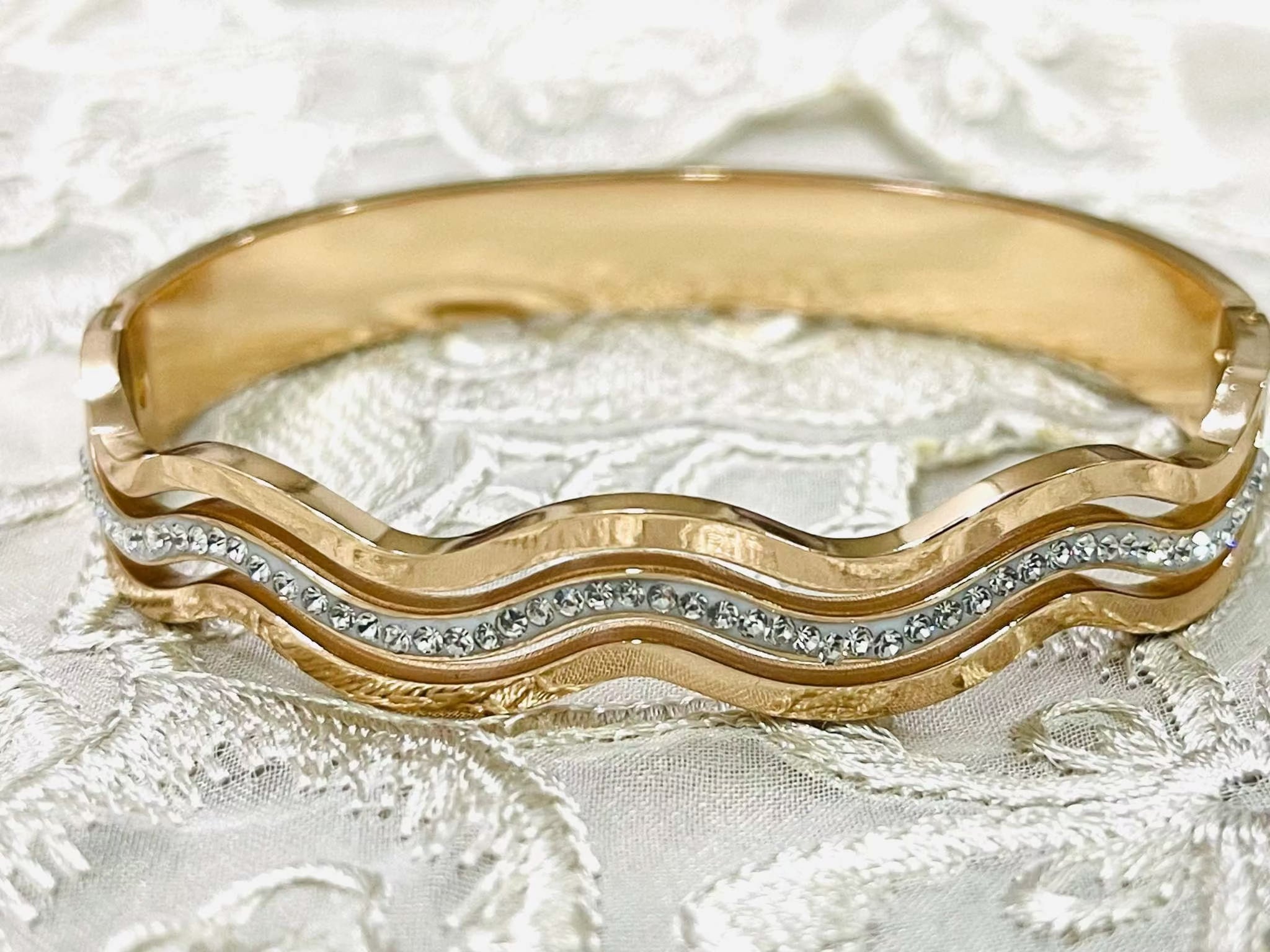 Rose gold bracelet with wave design and diamond accents on lace background