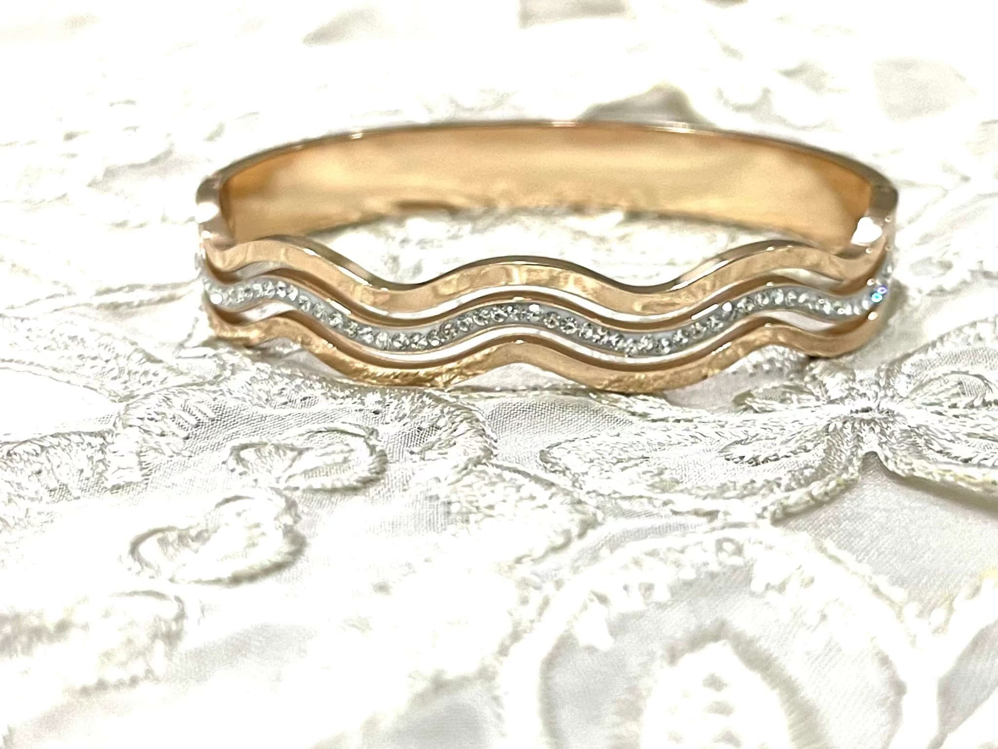 Rose gold bracelet with wave design and embedded diamonds on lace fabric background