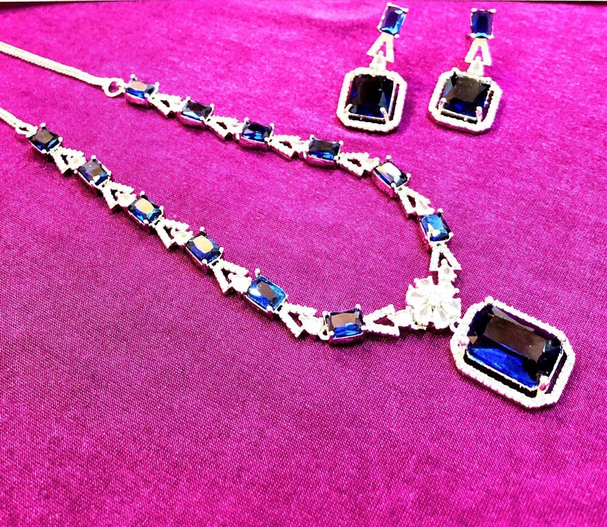 Indigo blue square crystal pendant necklace and matching earrings set on purple background