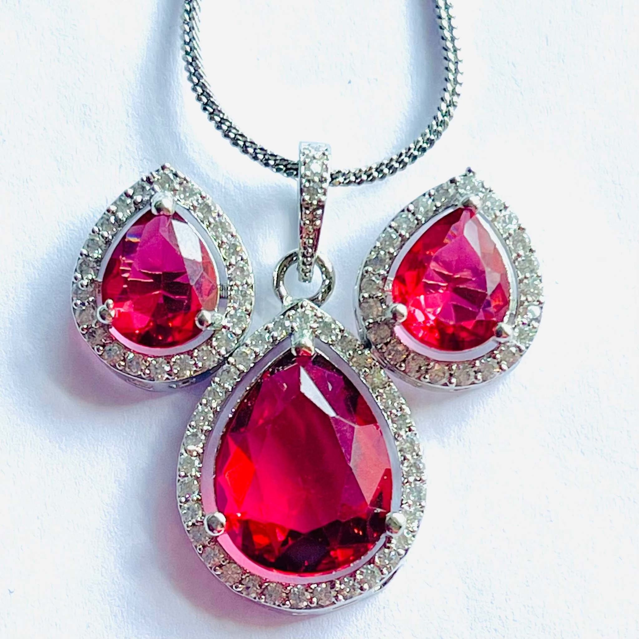 Blazing Red Aurora Drops pendant and earrings set with teardrop-shaped red gemstones surrounded by sparkling crystals on silver settings