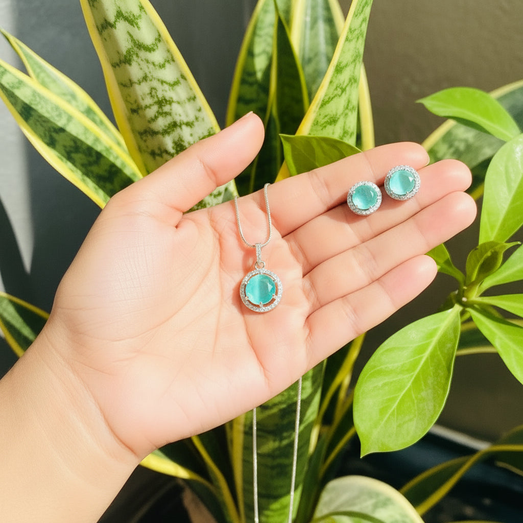 Teal Majestic Moonlit grand round pendant and earrings set with AD stones on silver chain against green leaves background