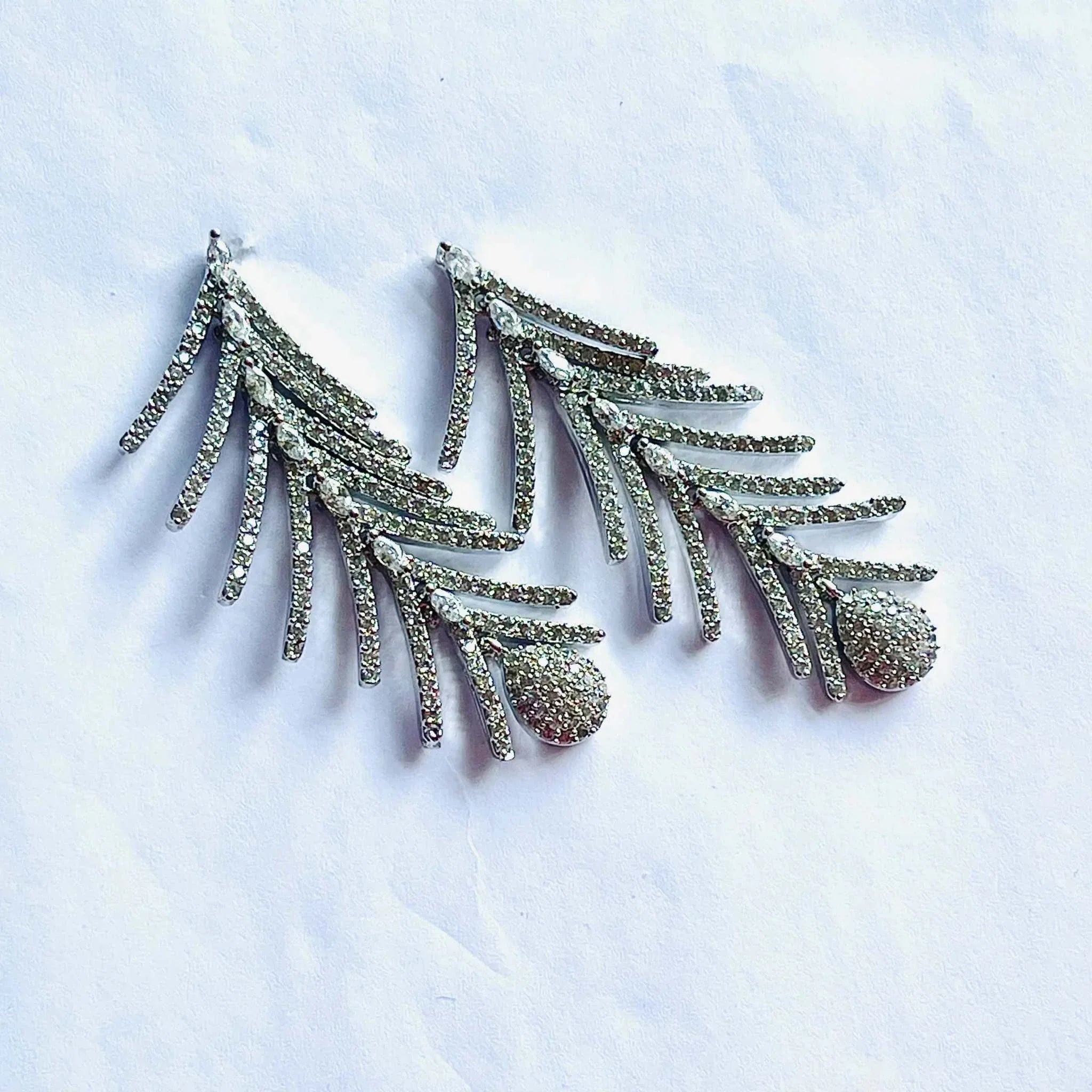 Silver feather dangling earrings encrusted with sparkling diamonds in intricate feather design