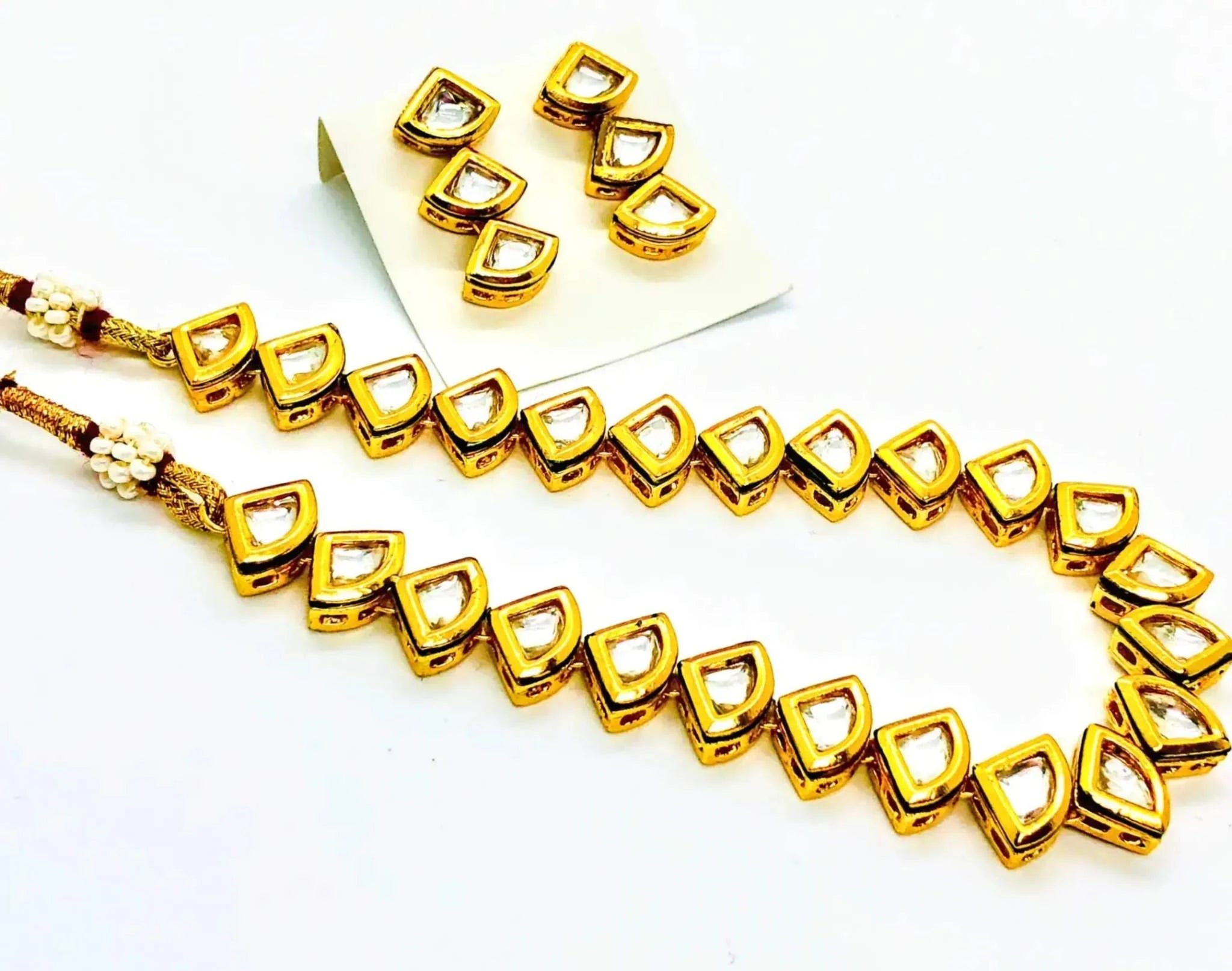 Golden and white triangular kundan necklace and earrings set with intricate craftsmanship and modern design