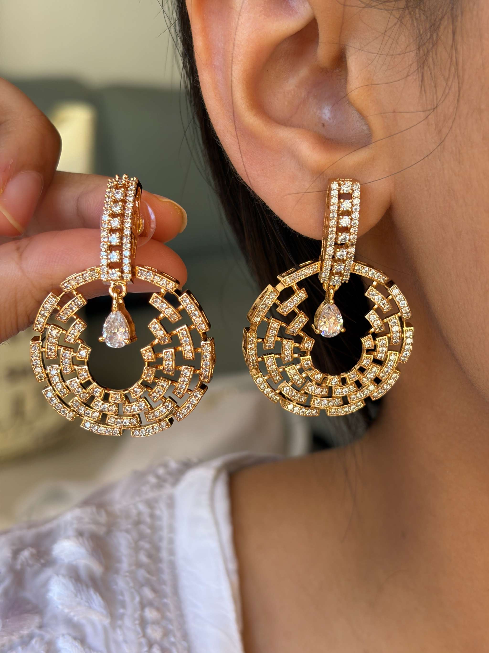 Close-up of rose gold Celestial Maze Danglers earrings with intricate maze pattern and sparkling stones worn on ear