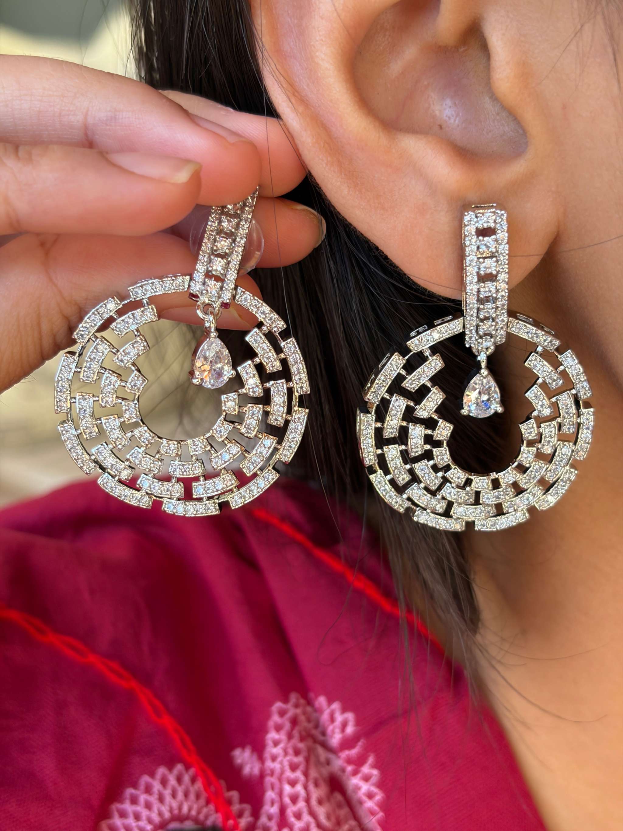 Close-up of silver Celestial Maze Danglers earrings with intricate geometric design and dangling teardrop gemstone on a woman's ear