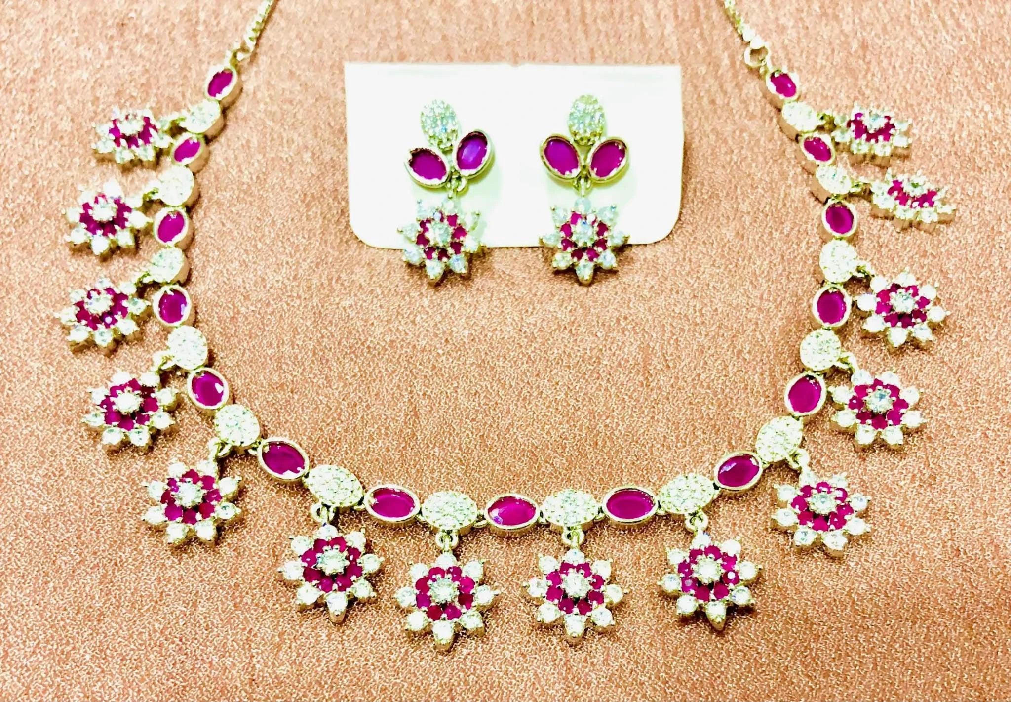 White and burgundy crystal necklace and earrings set on a glittery surface