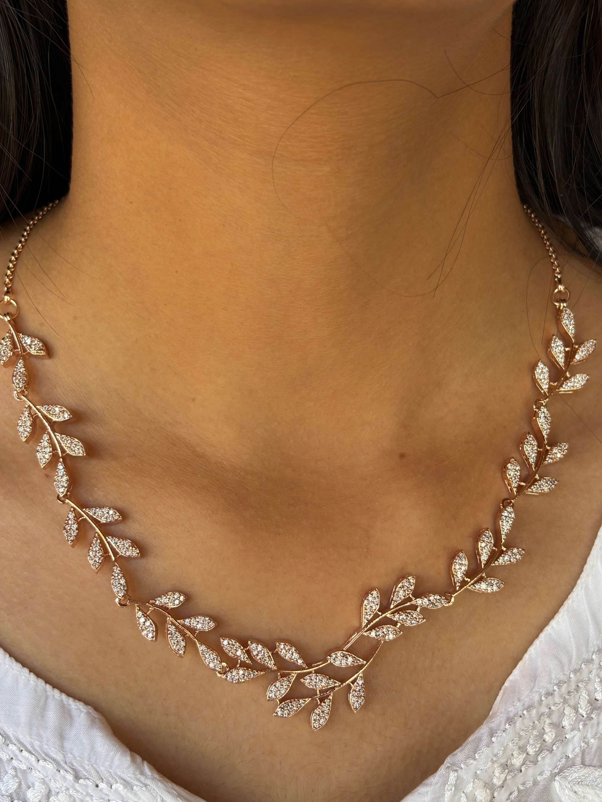 Leafy Embrace Necklace in rosegold with delicate leaf motifs and sparkling details on a woman's neck