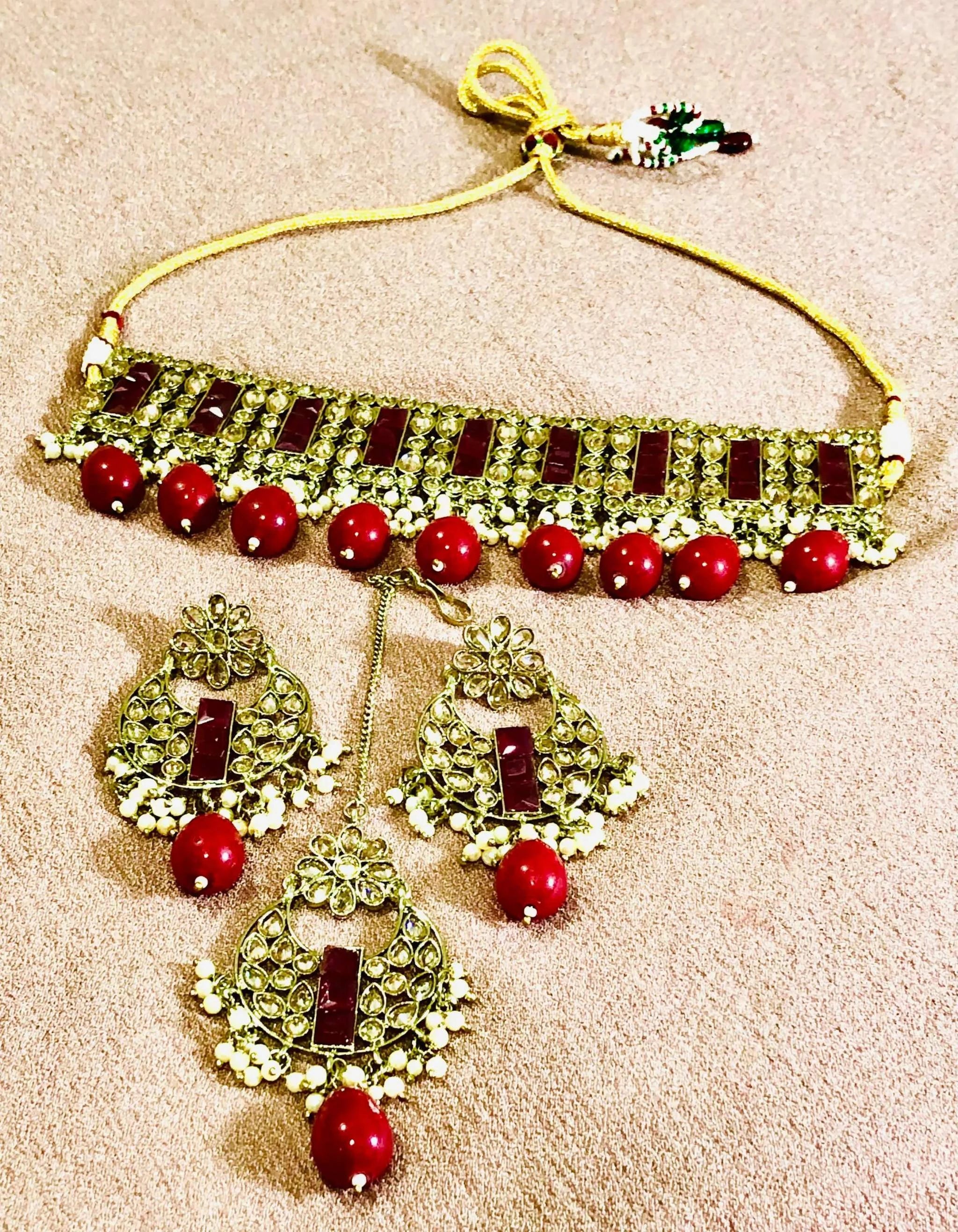 Elegant rose red Rajwadi jewelry set with traditional gold detailing, featuring a choker necklace and matching earrings with red gemstones.