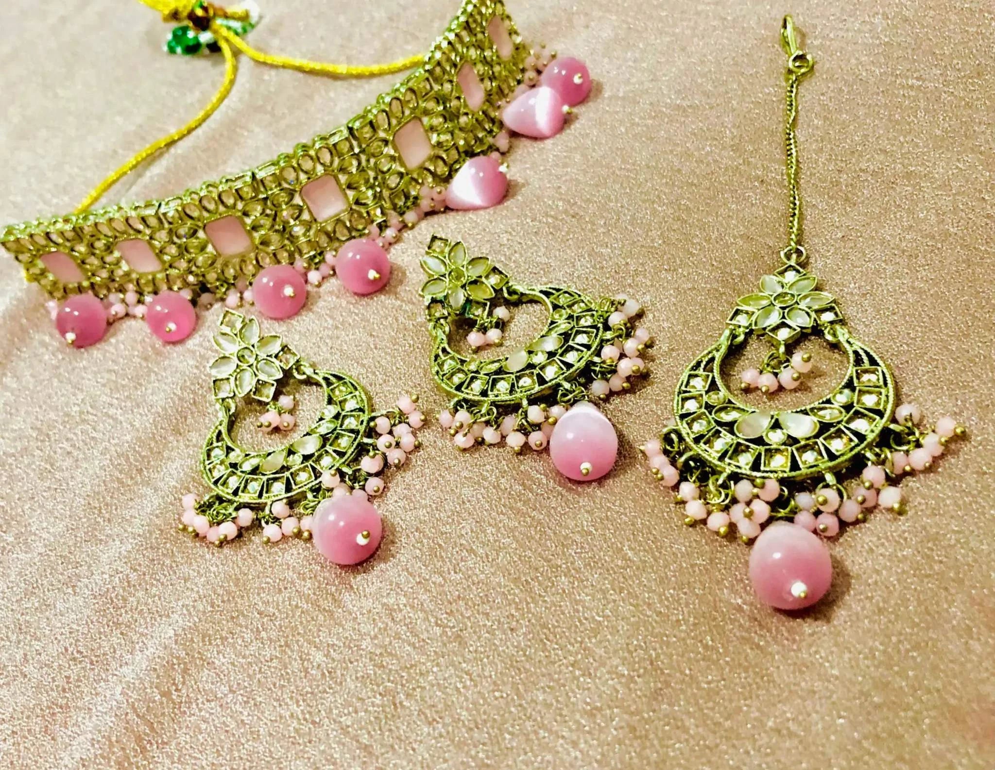 Charming Pink Rajawadi Jewelry Ensemble including gold-toned choker, earrings, and matching maang tikka with pink beads and intricate floral designs