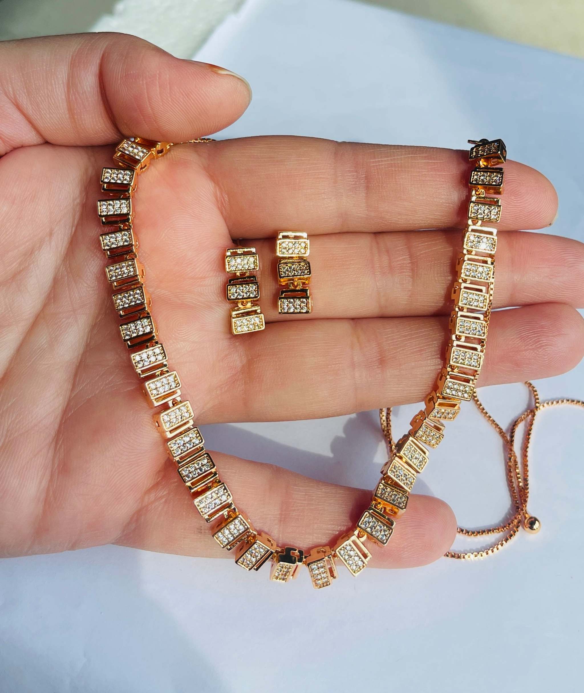 Classic rose gold zircon necklace and earring set held in hand, showcasing elegant rectangular links with sparkling stones, perfect for timeless style and sophistication