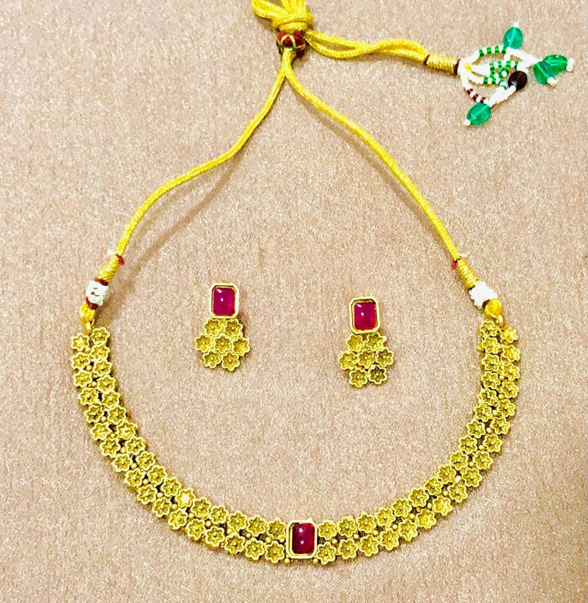 Golden Rajwadi choker necklace set with traditional floral design and ruby-studded earrings