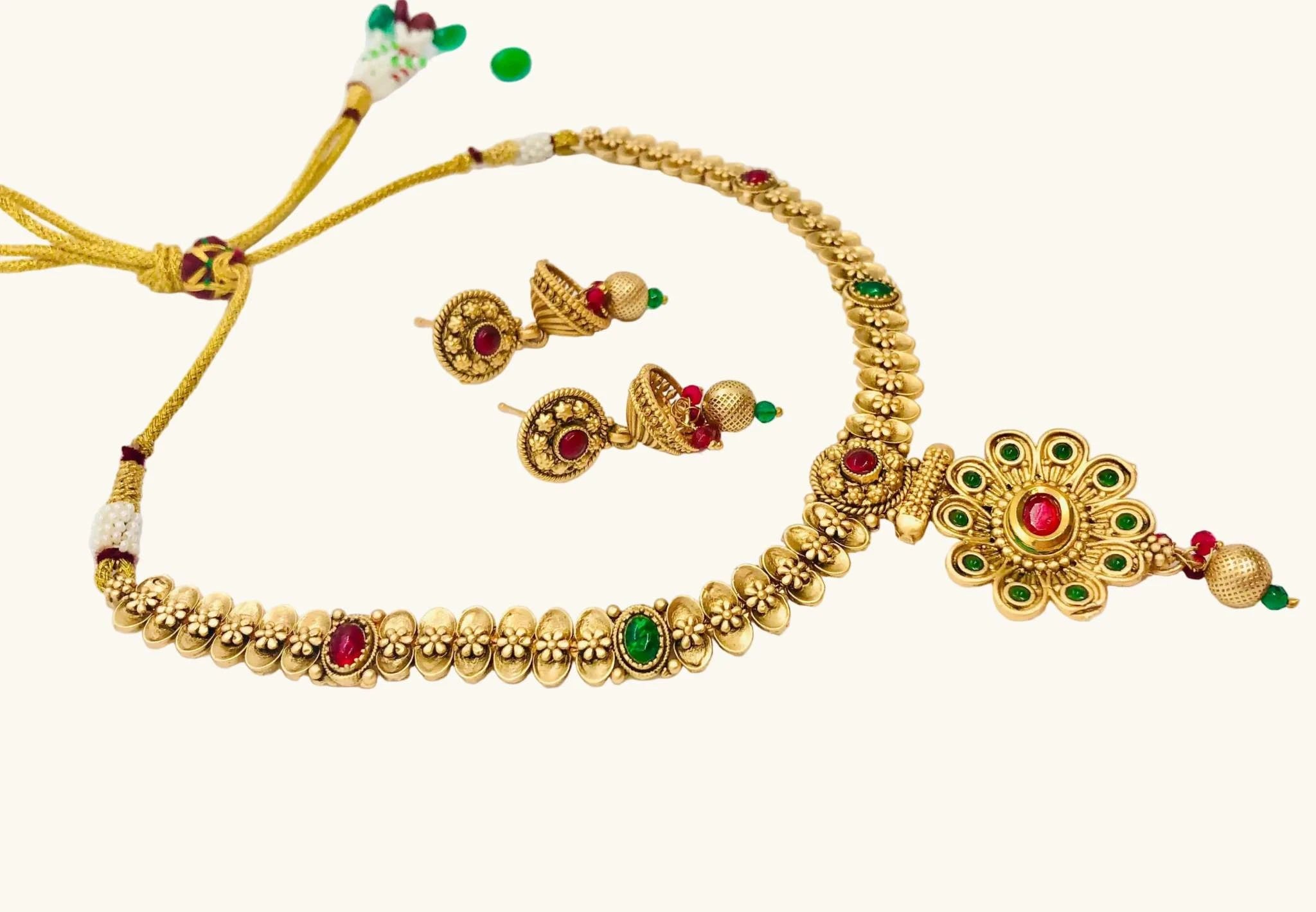 Rajwadi golden necklace set with red and green meenakari stones and matching earrings on white background
