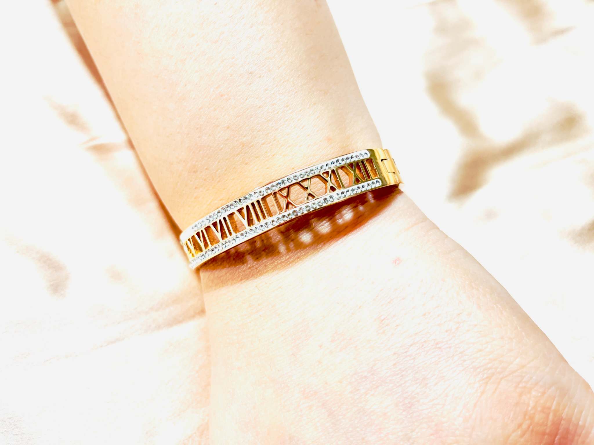 Rose gold bracelet with engraved Roman numerals and diamond accents on wrist