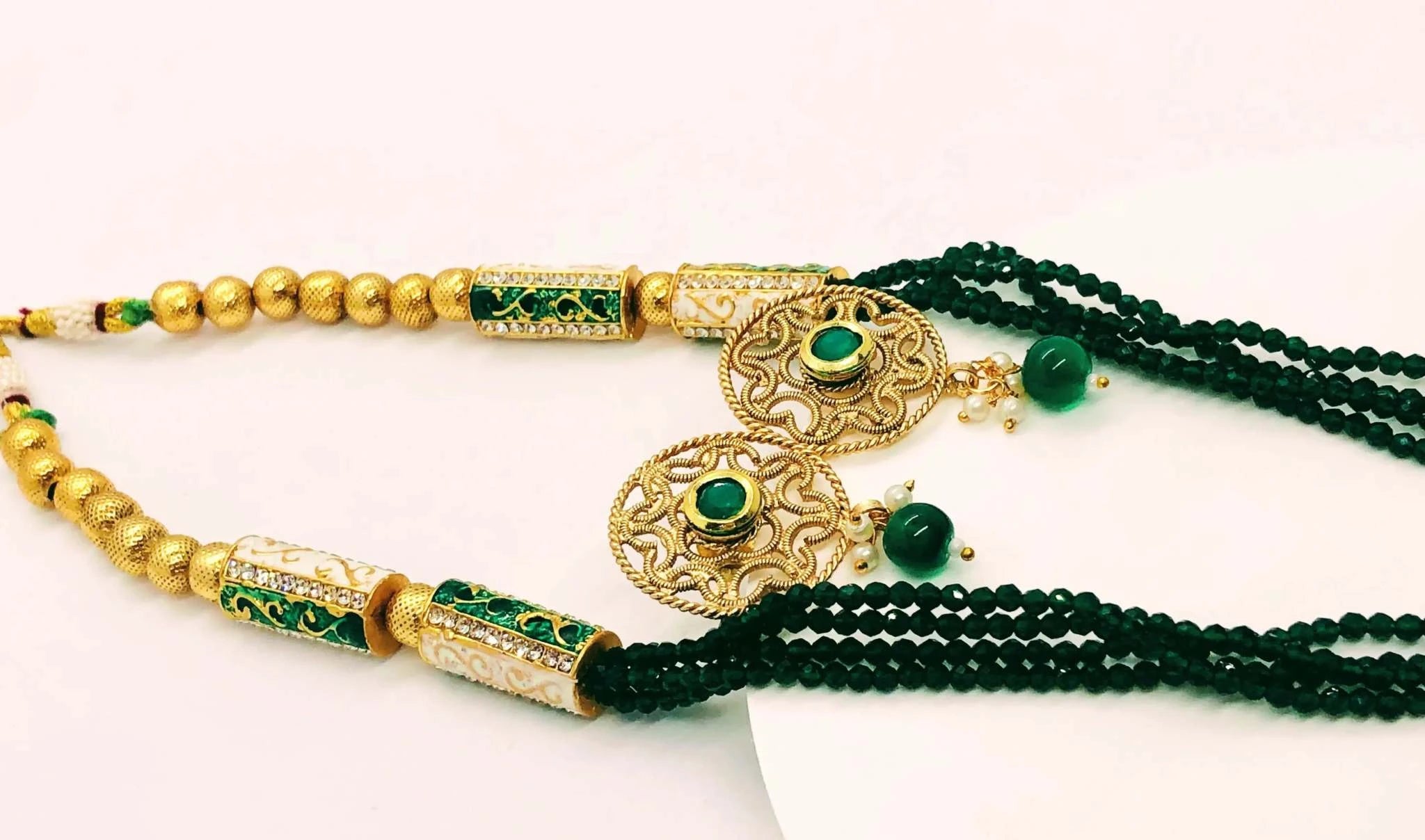 Golden and emerald beaded jewelry set featuring intricately designed earrings and a matching necklace with vibrant green beads and gold accents