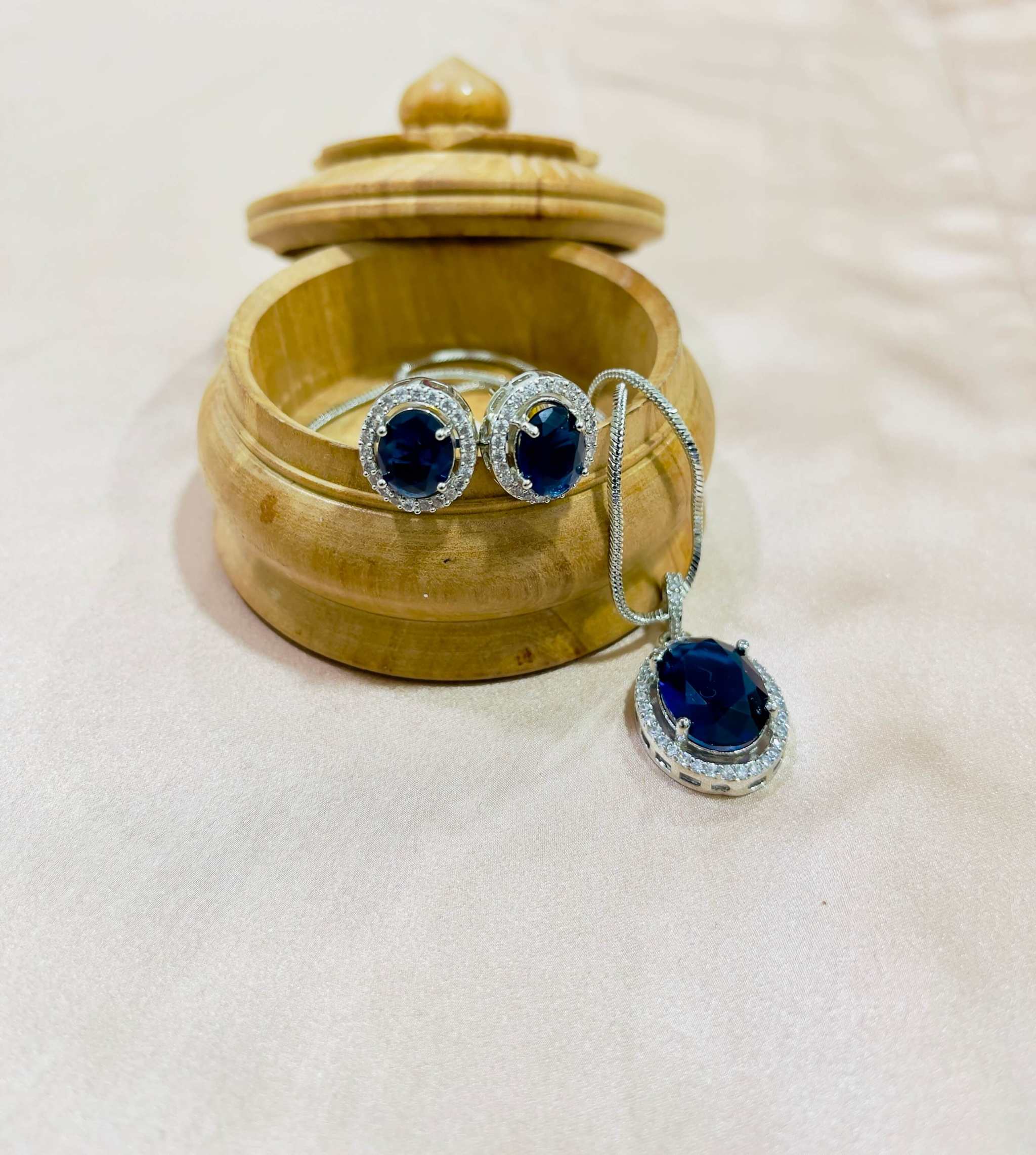 Blue and silver oval pendant and earrings set with AD stones in a wooden jewelry box