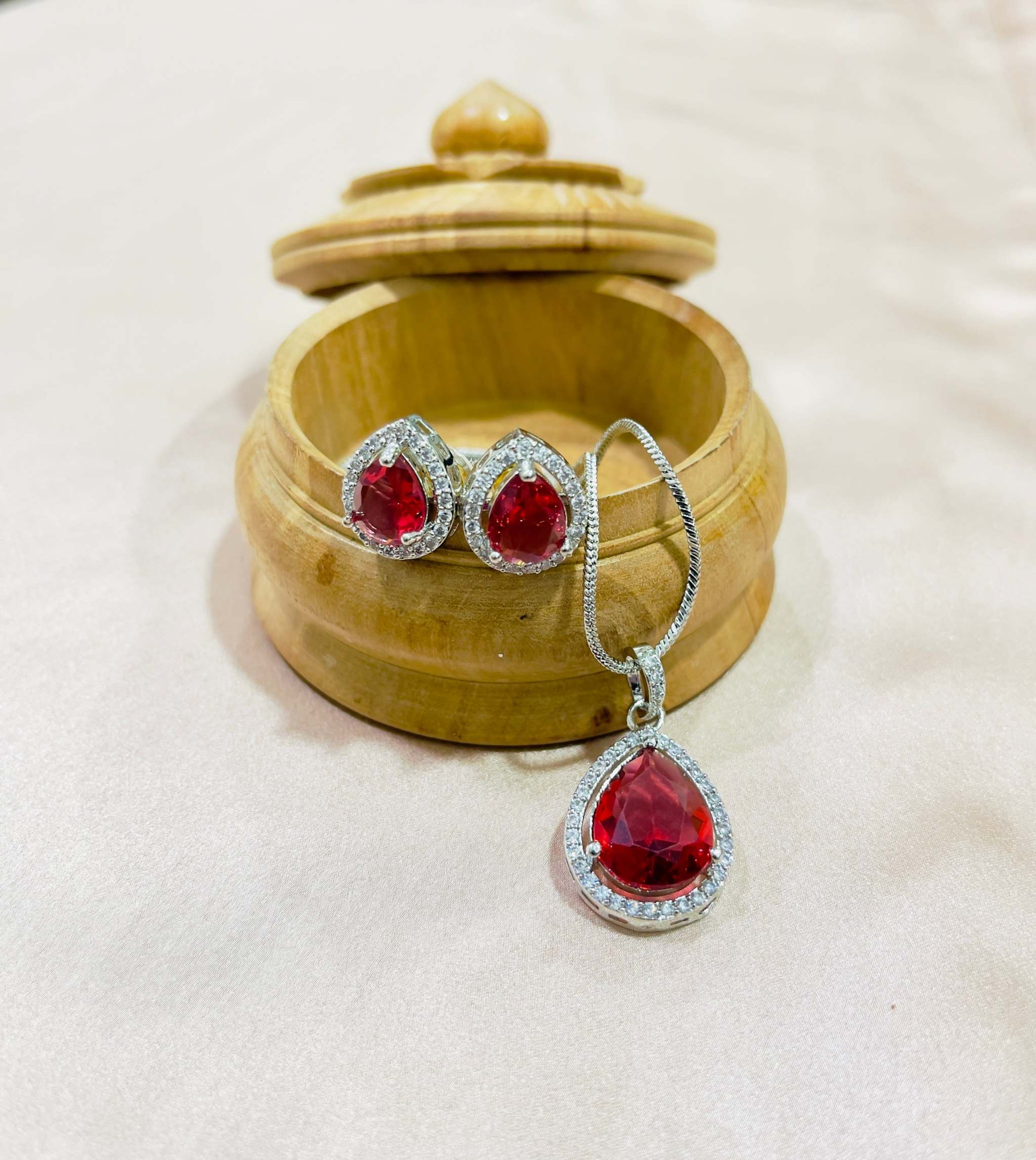 Blazing Red Aurora Drops Grand Pendant Set with teardrop red gemstones and silver accents displayed on a wooden jewelry box