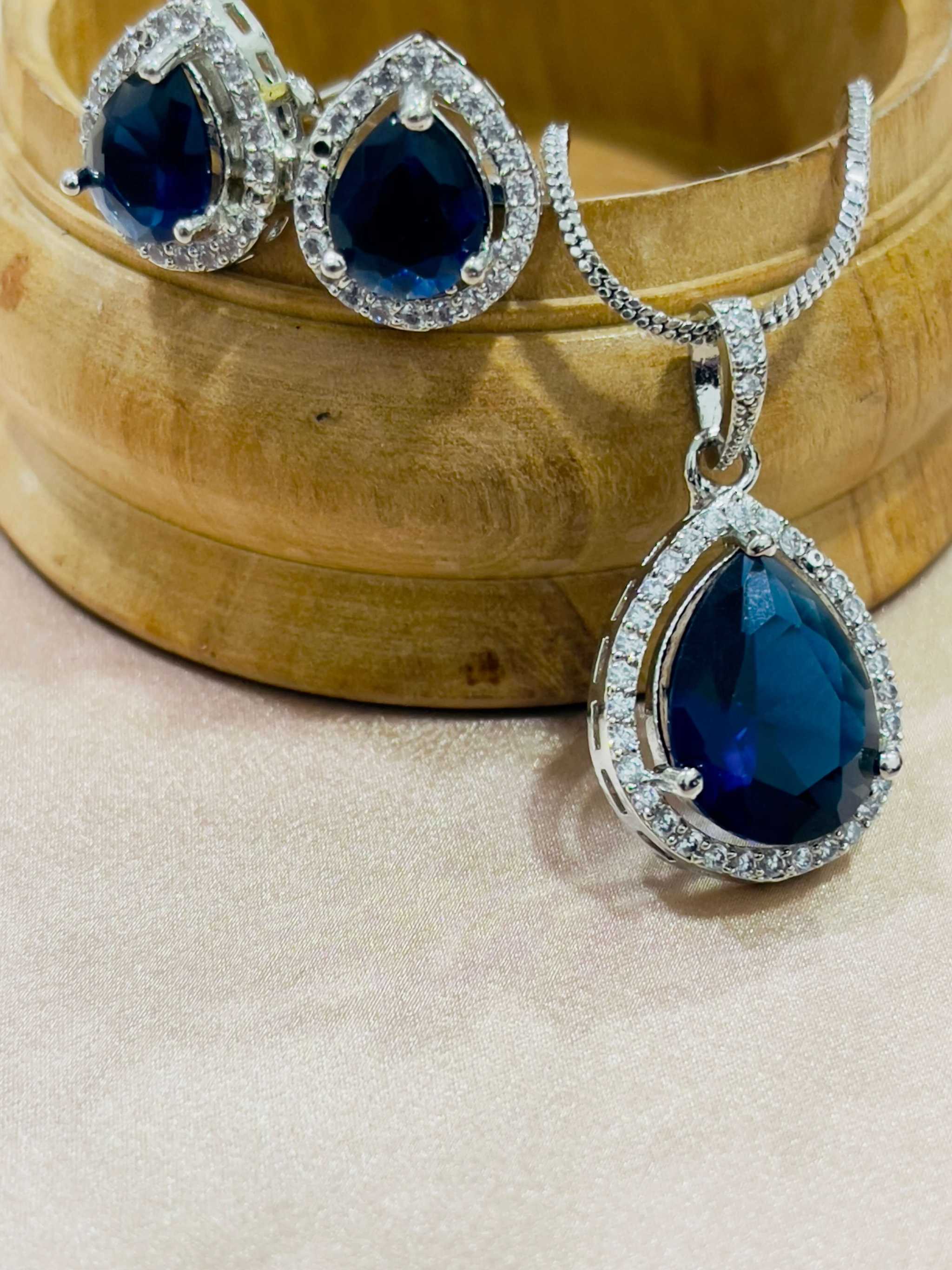 Indigo Grand Pendant Set featuring deep blue teardrop gemstones with surrounding clear crystals on silver chain and matching earrings