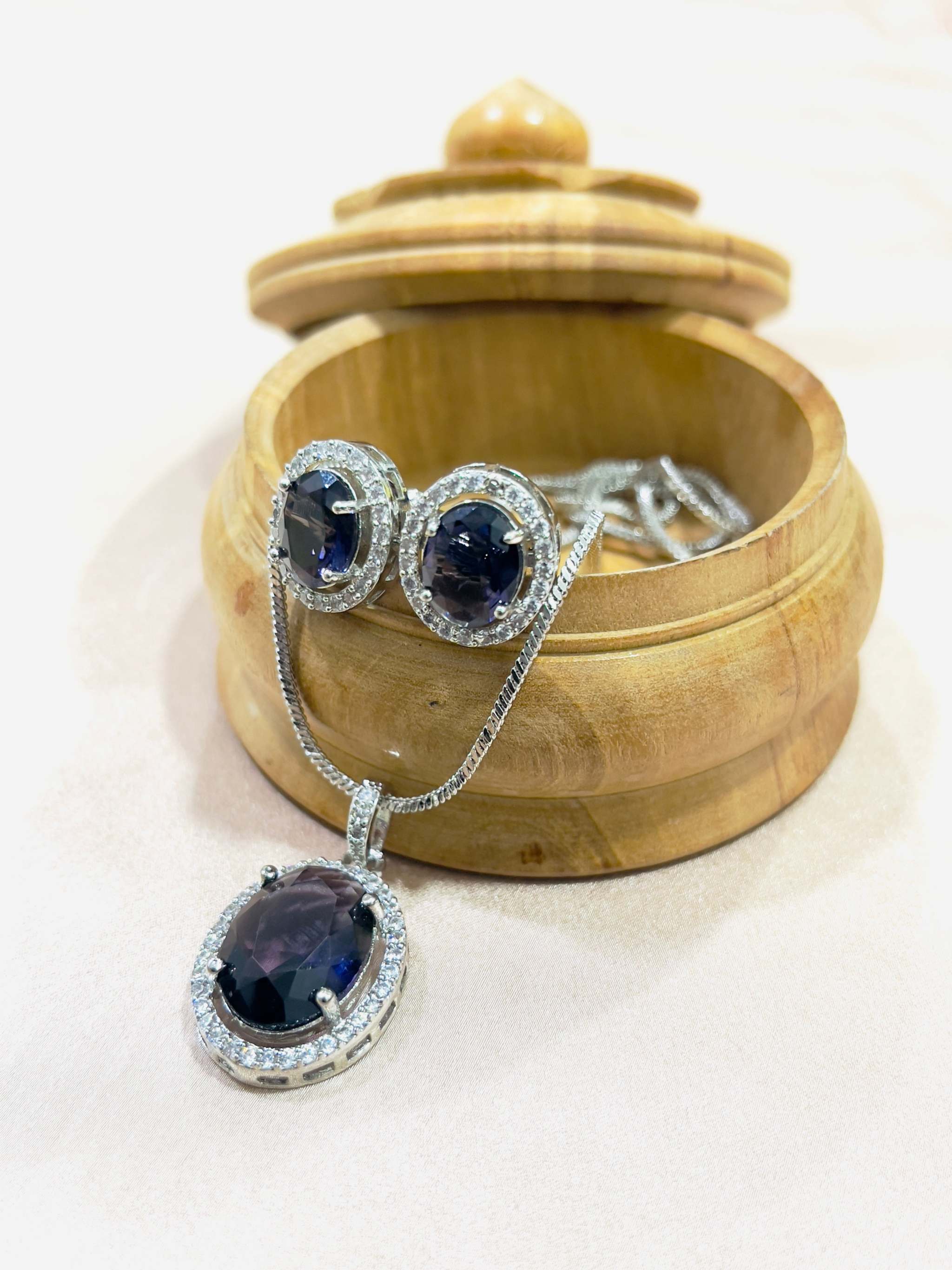 Violet Oval Grand Pendant Set with violet gemstones and silver chain displayed on wooden box