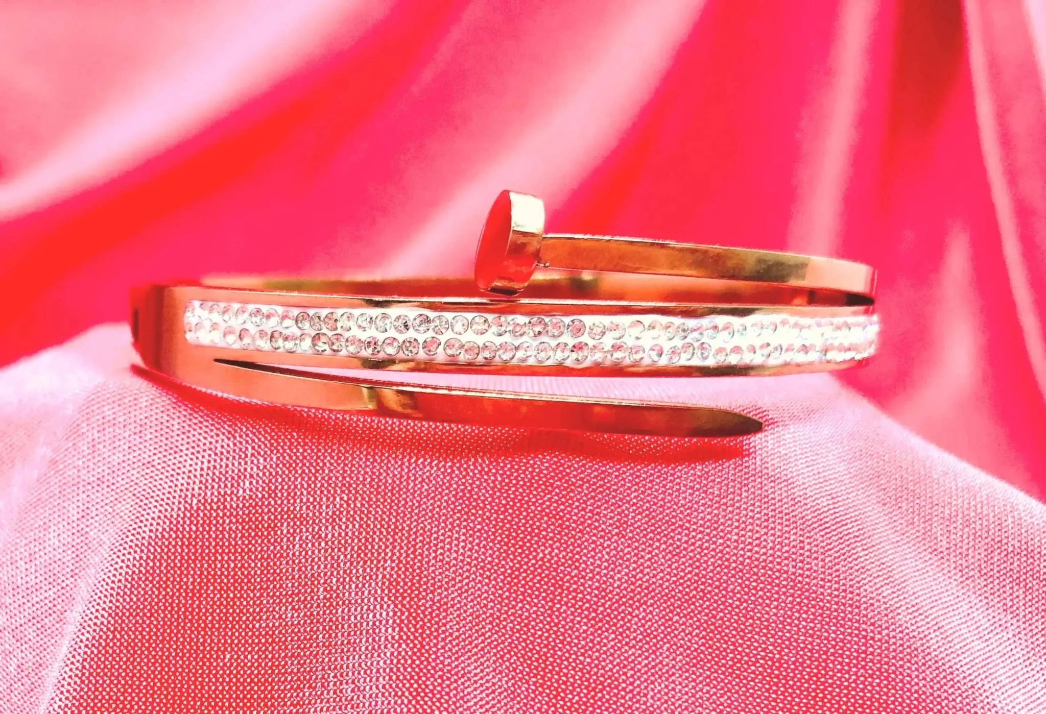 Elegant gold Korean bracelet with white diamond accents on pink fabric background