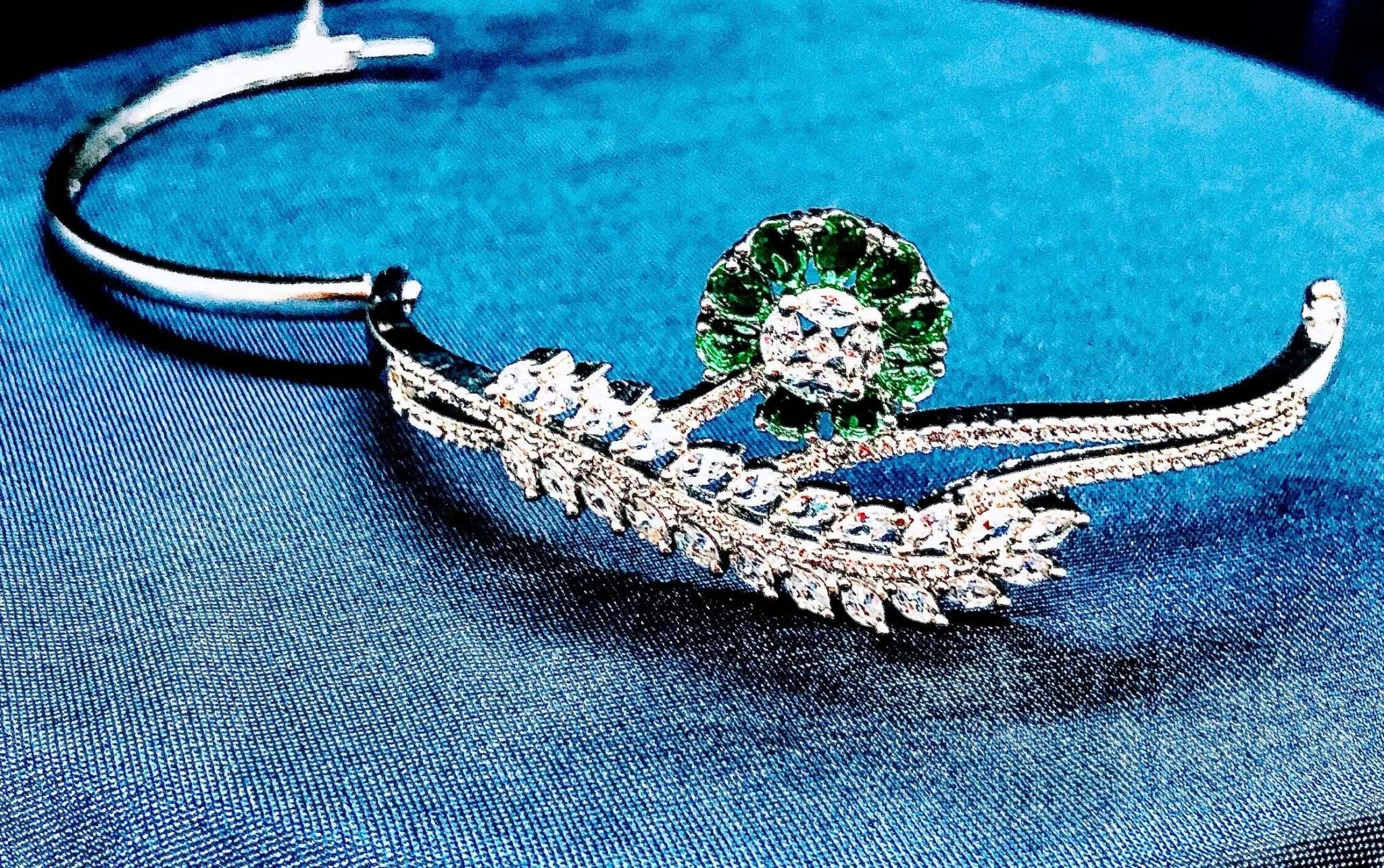 Silver bracelet with emerald floral design featuring green stones and intricate leaf details, elegant and versatile jewelry accessory