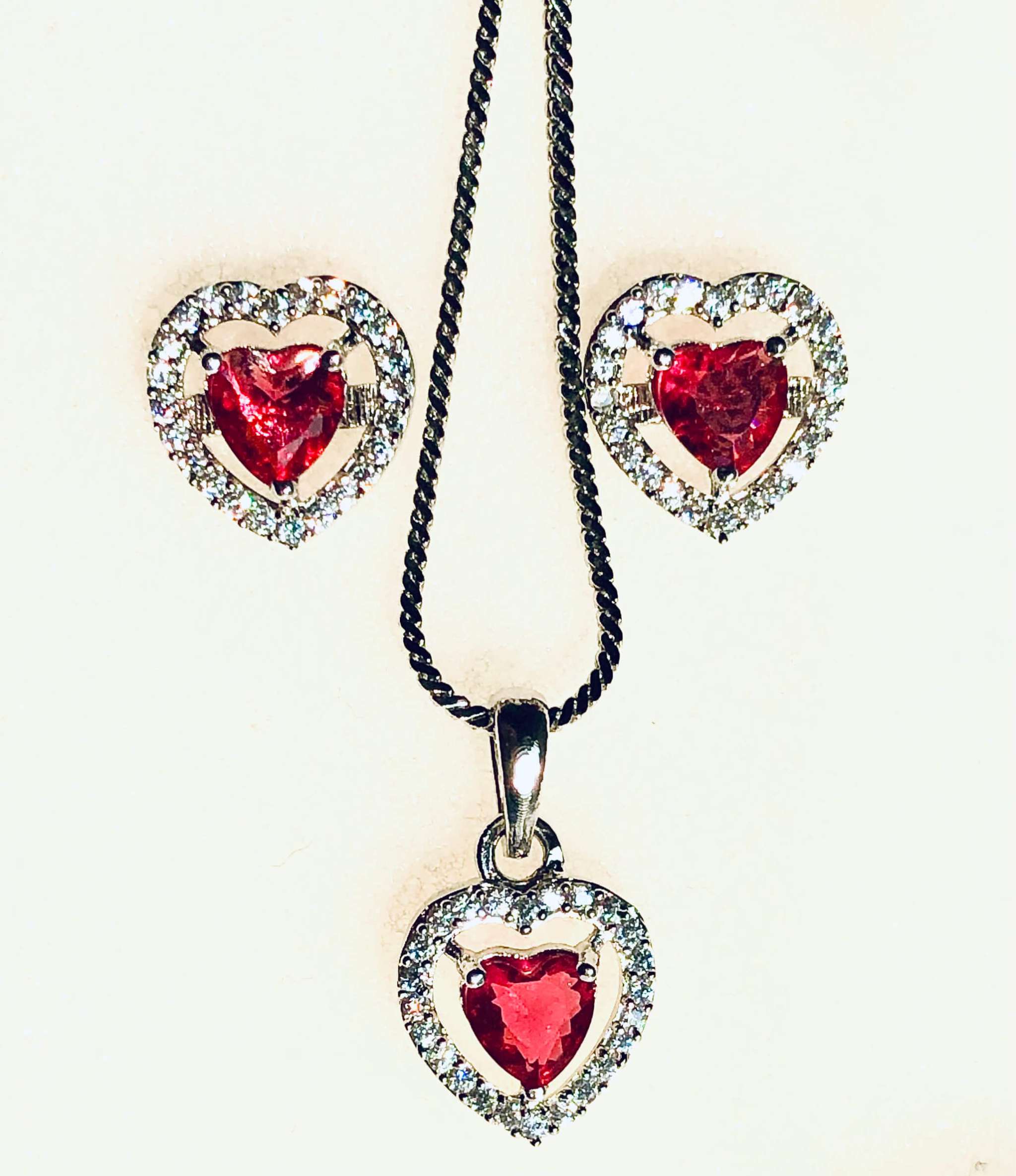 Silver and red heart-shaped pendant and earrings set with AD stones on a chain necklace