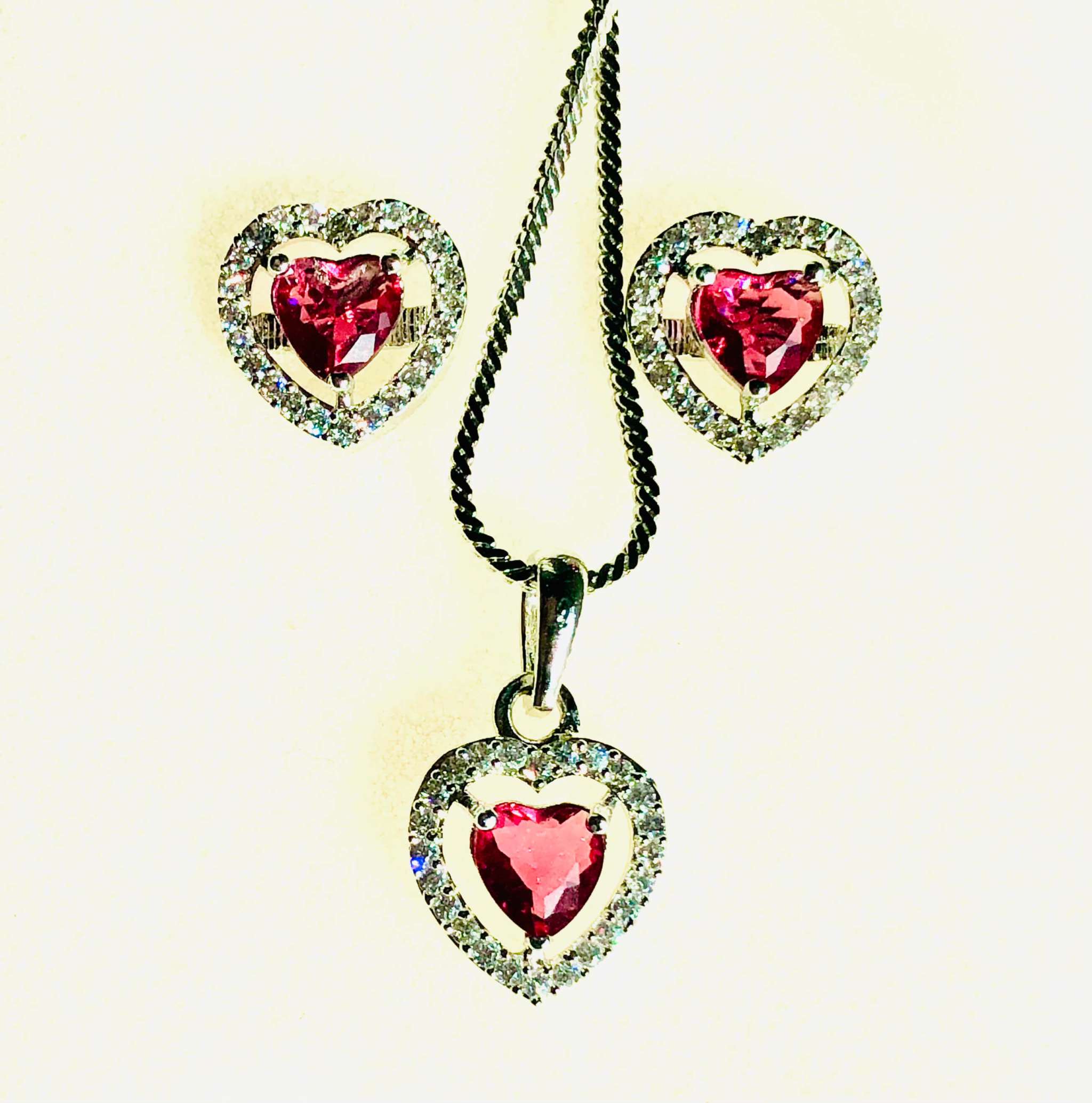 Silver and red heart-shaped pendant and earrings set with sparkling AD stones on silver chain necklace