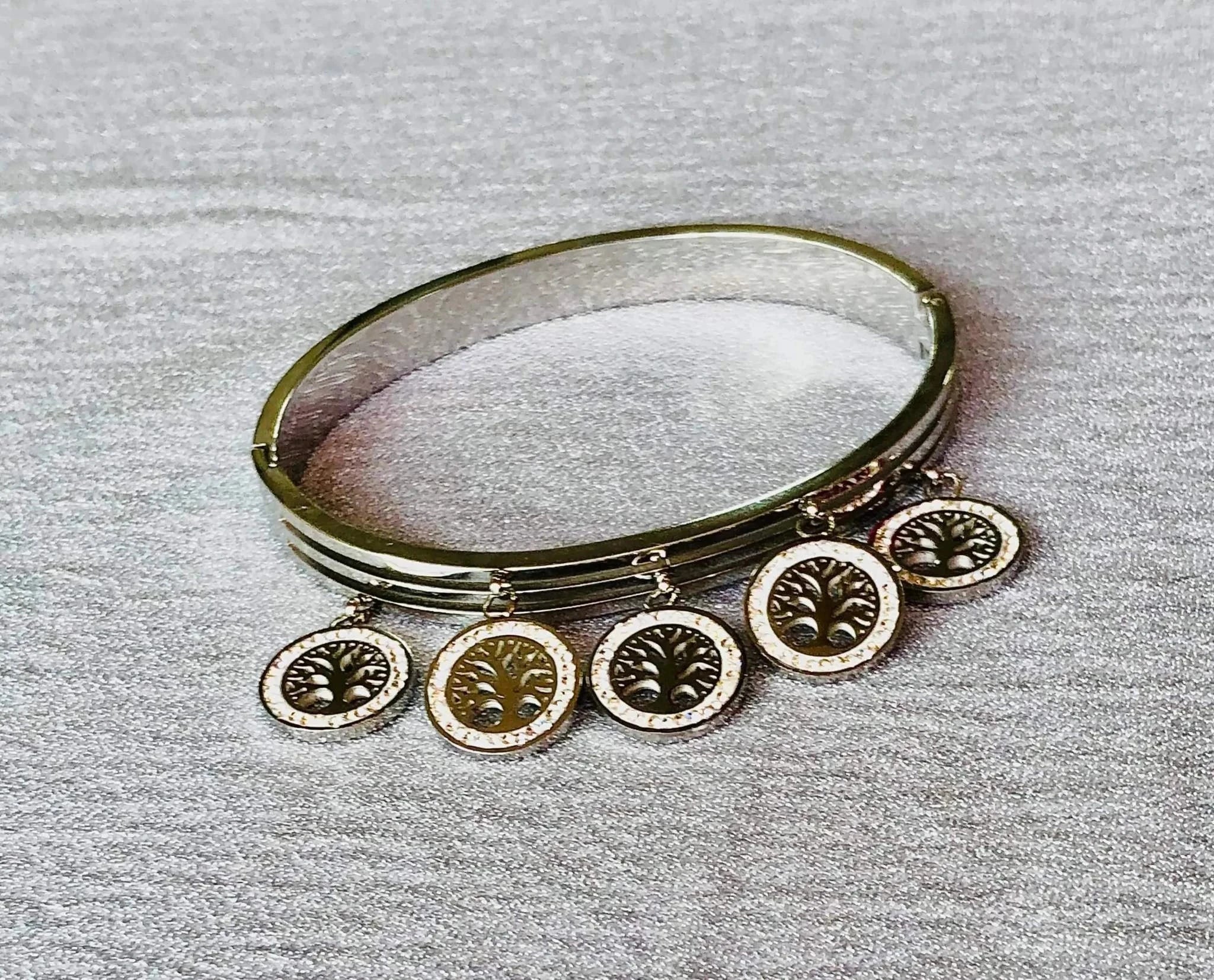 Silver Korean-style bracelet with anti-tarnish finish and five tree of life charms on a textured gray surface