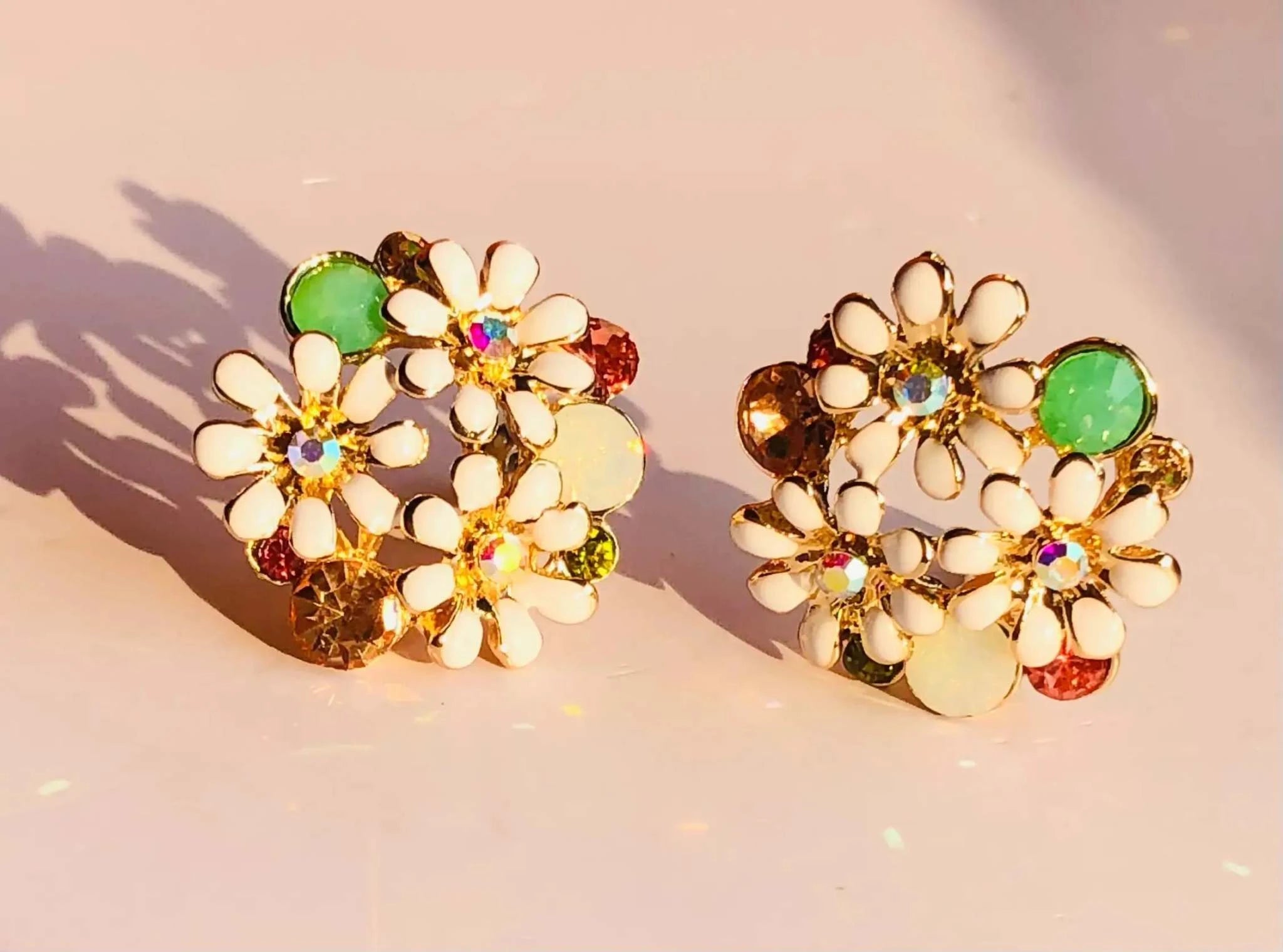Rose gold and white enamel floral stud earrings with multicolored gemstone accents