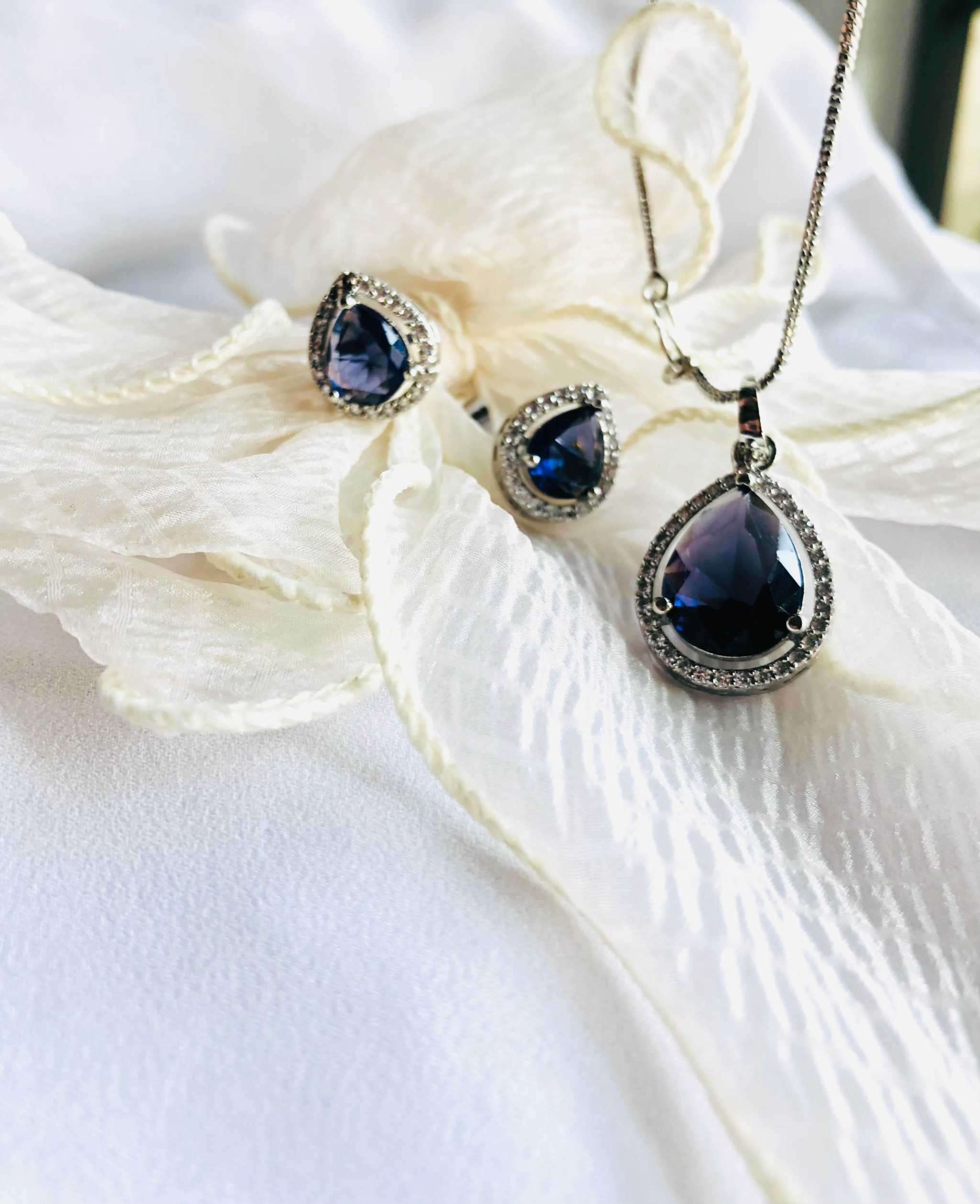 Violet and silver teardrop grand pendant set with matching earrings on white fabric