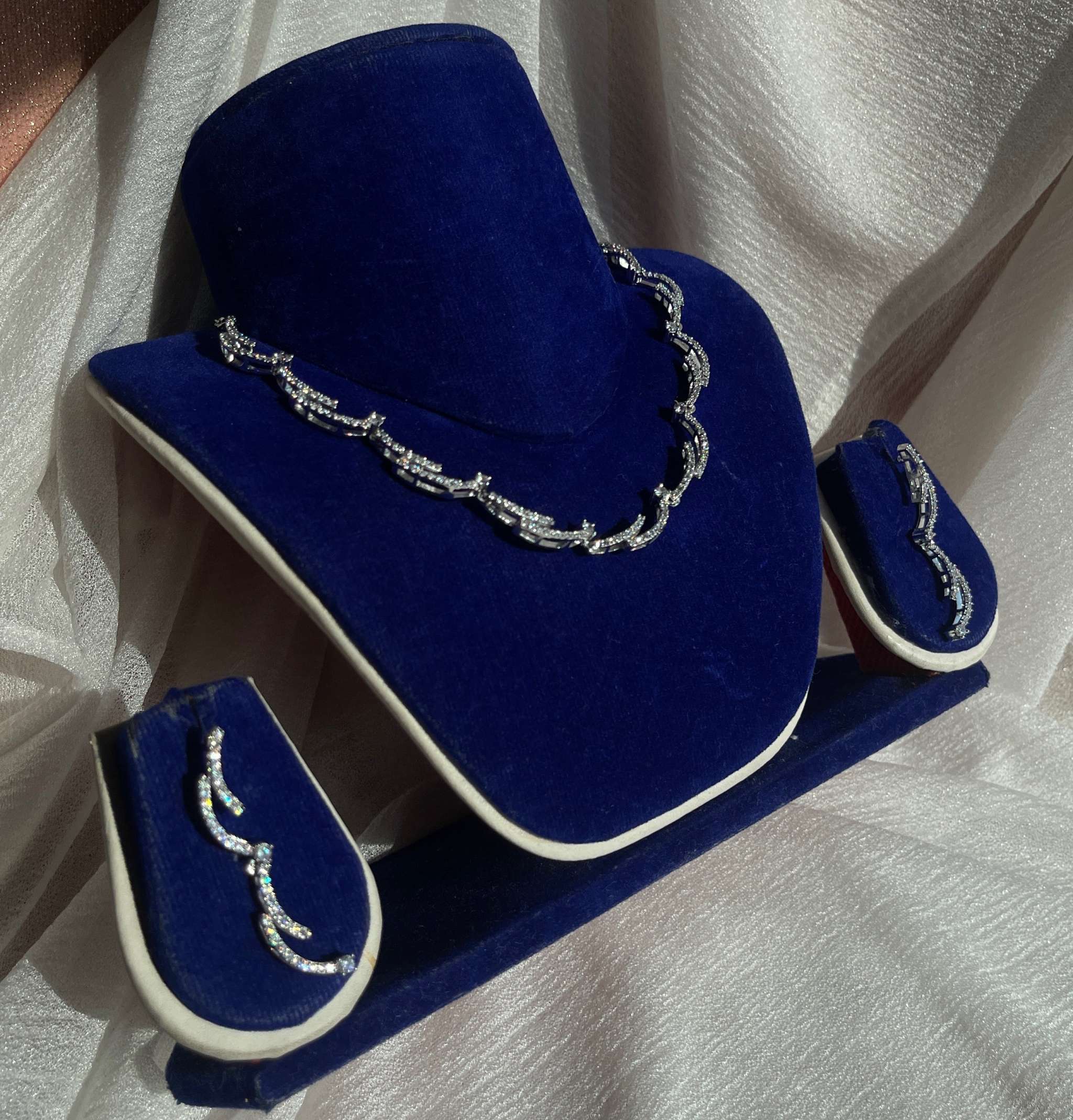 Silver crescent silhouette necklace set with matching earrings on blue velvet display