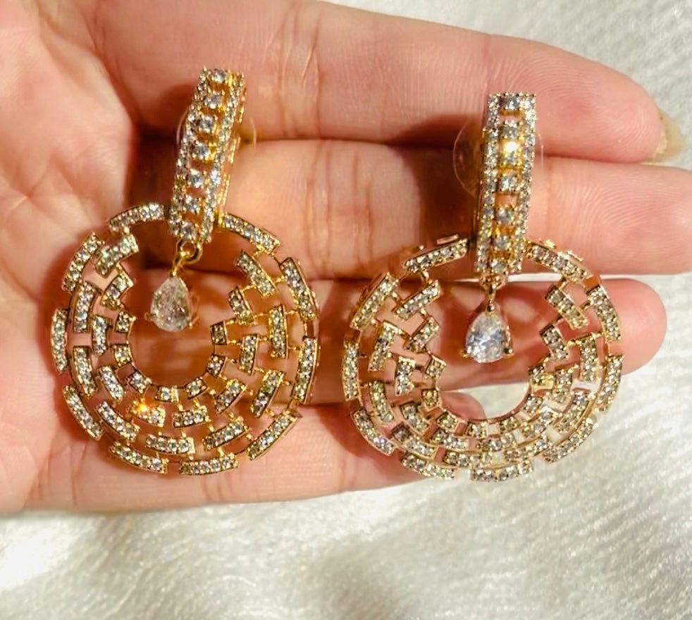 Rose gold Celestial Maze Danglers earrings with intricate maze design and sparkling stones held in hand