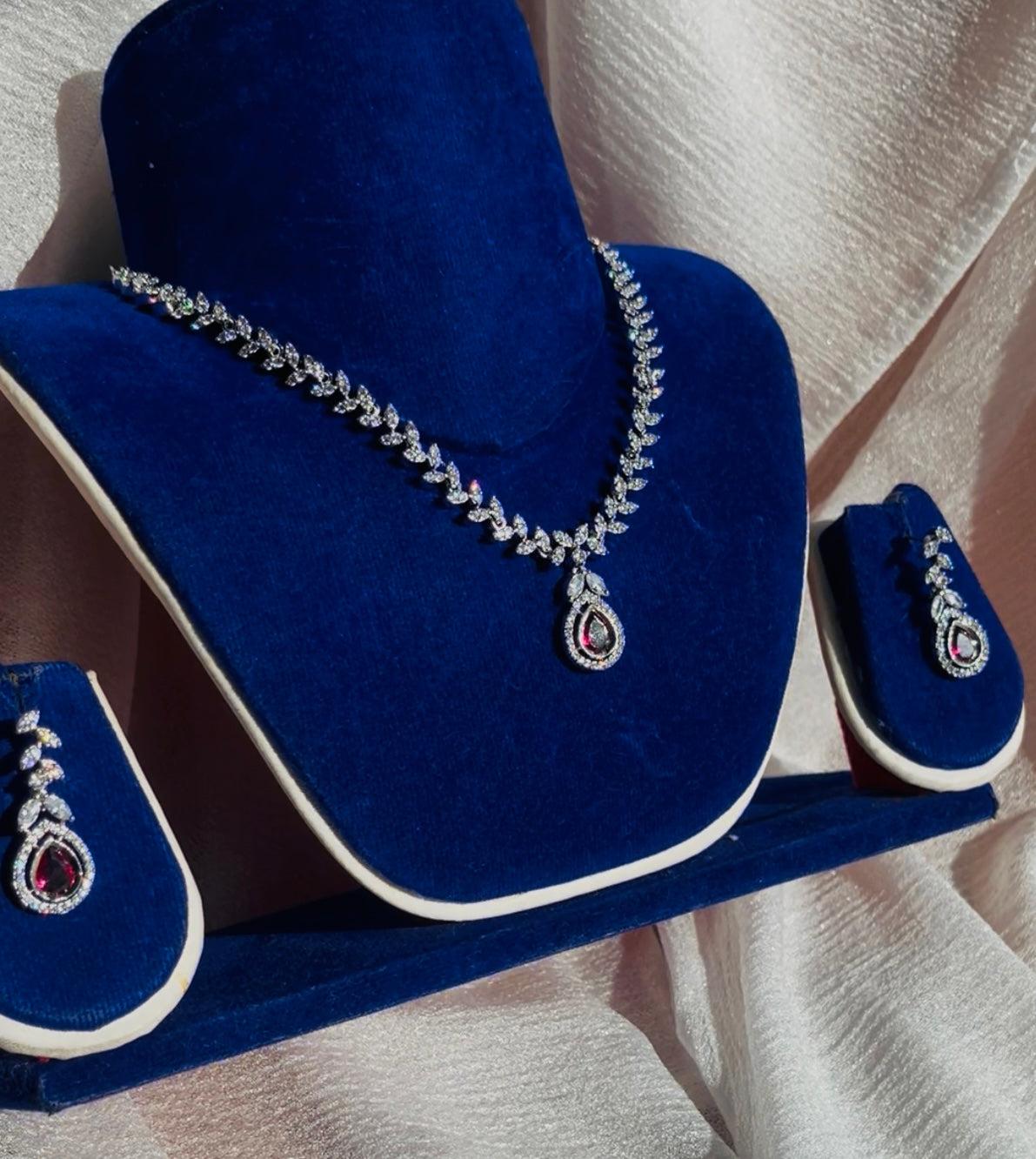 Scarlet Dew Necklace set in silver with bold scarlet accents and dew drop design displayed on blue velvet stand