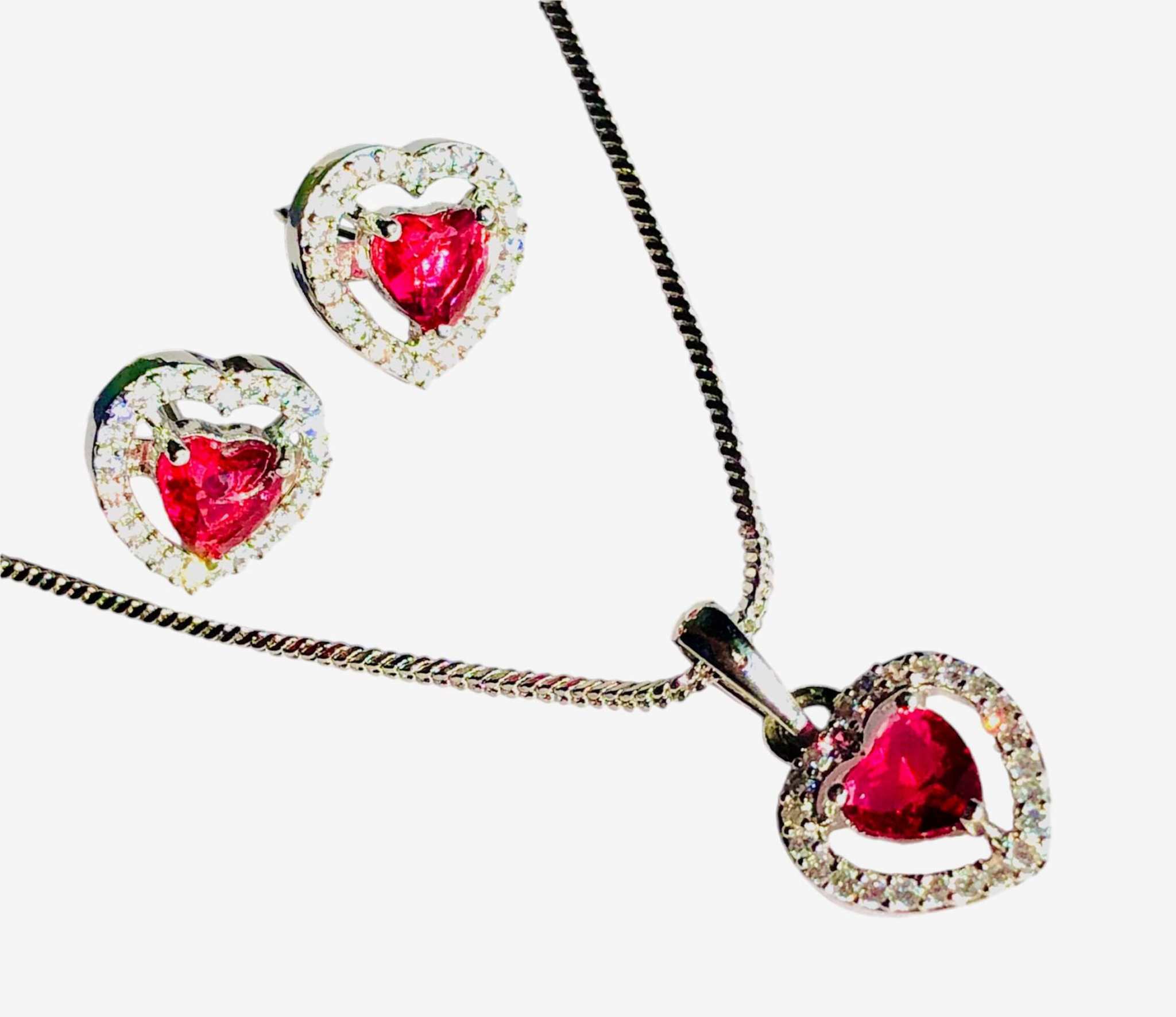 Silver and red heart pendant set with AD stones featuring a silver chain necklace and matching earrings with red heart-shaped stones surrounded by clear crystals
