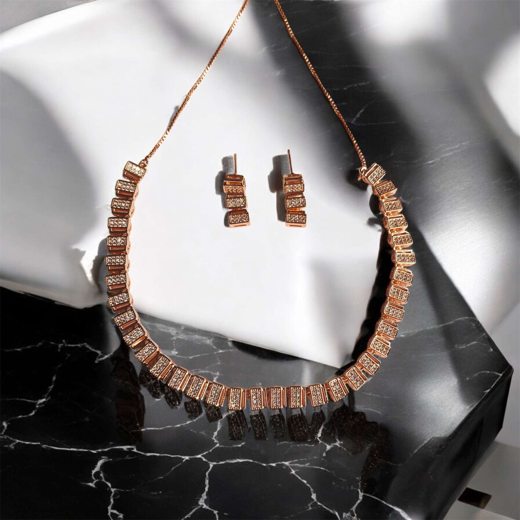 Classic rose gold zircon necklace and matching earrings set on black and white marble background
