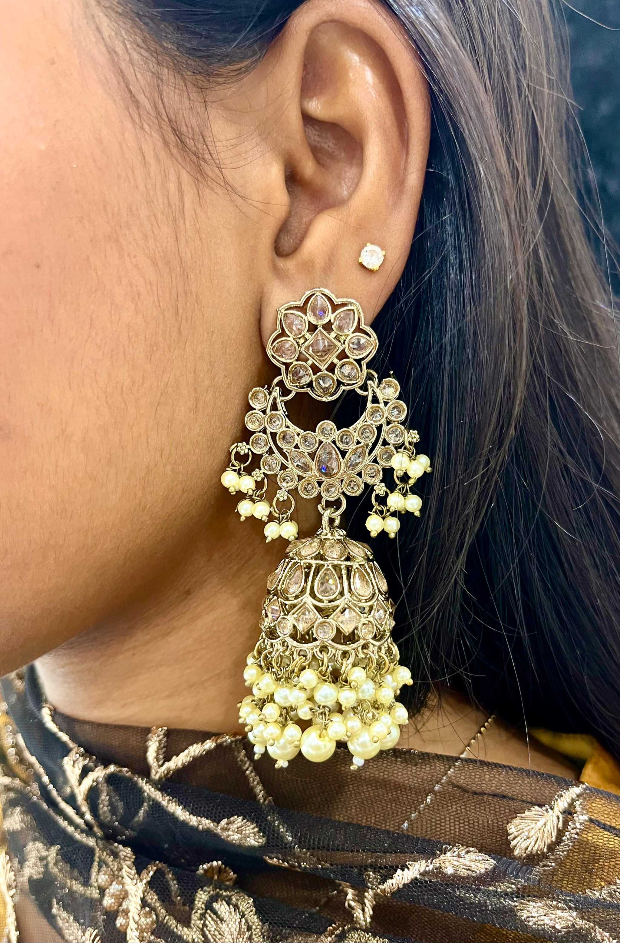 Close-up of a cascading long jhumkas earring with tiered floral design and pearl accents worn on the ear