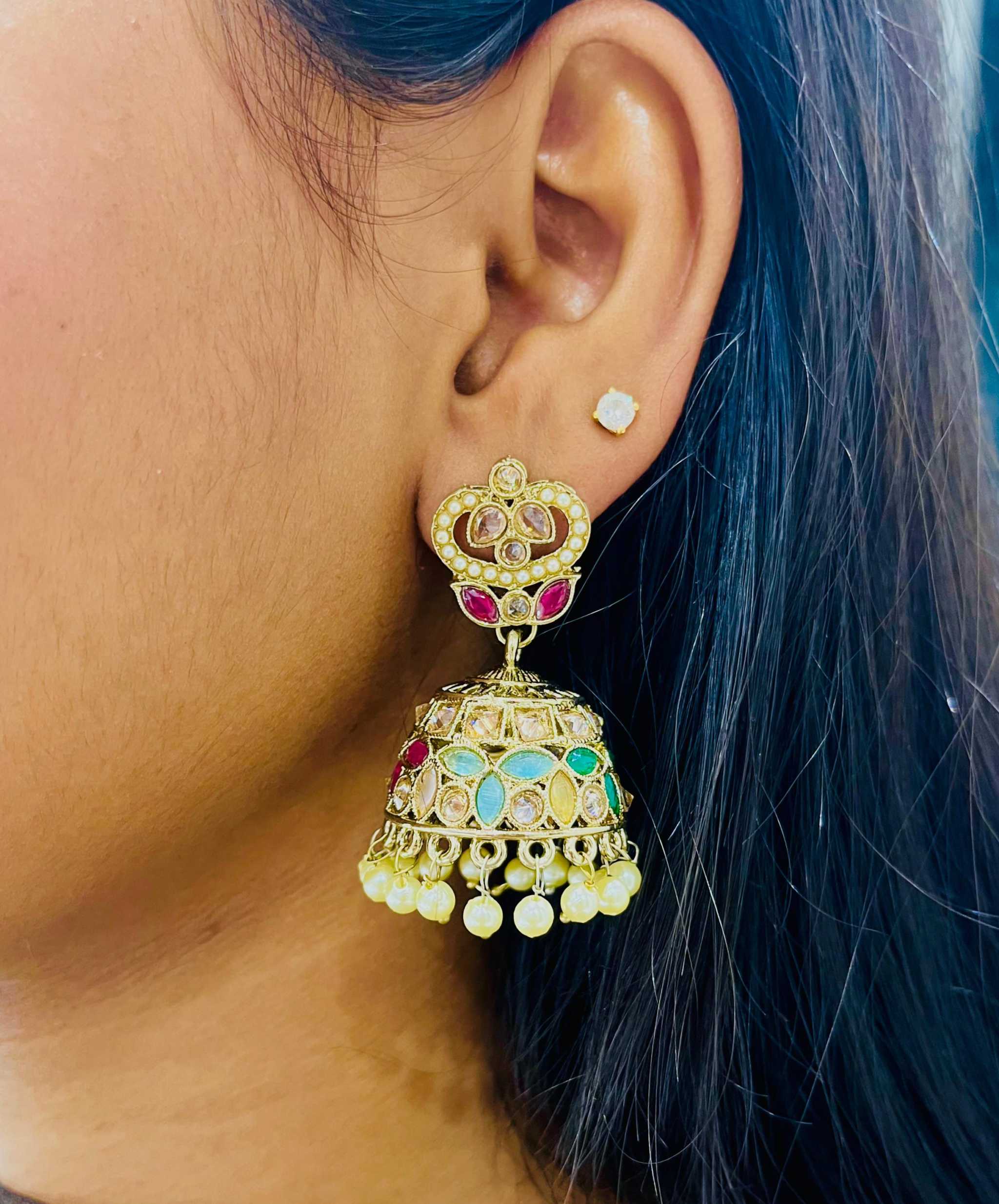 Close-up of a woman's ear wearing colorful Rangeen Taj Jhumkas with intricate enamel work, sparkling stones, and dangling pearls.
