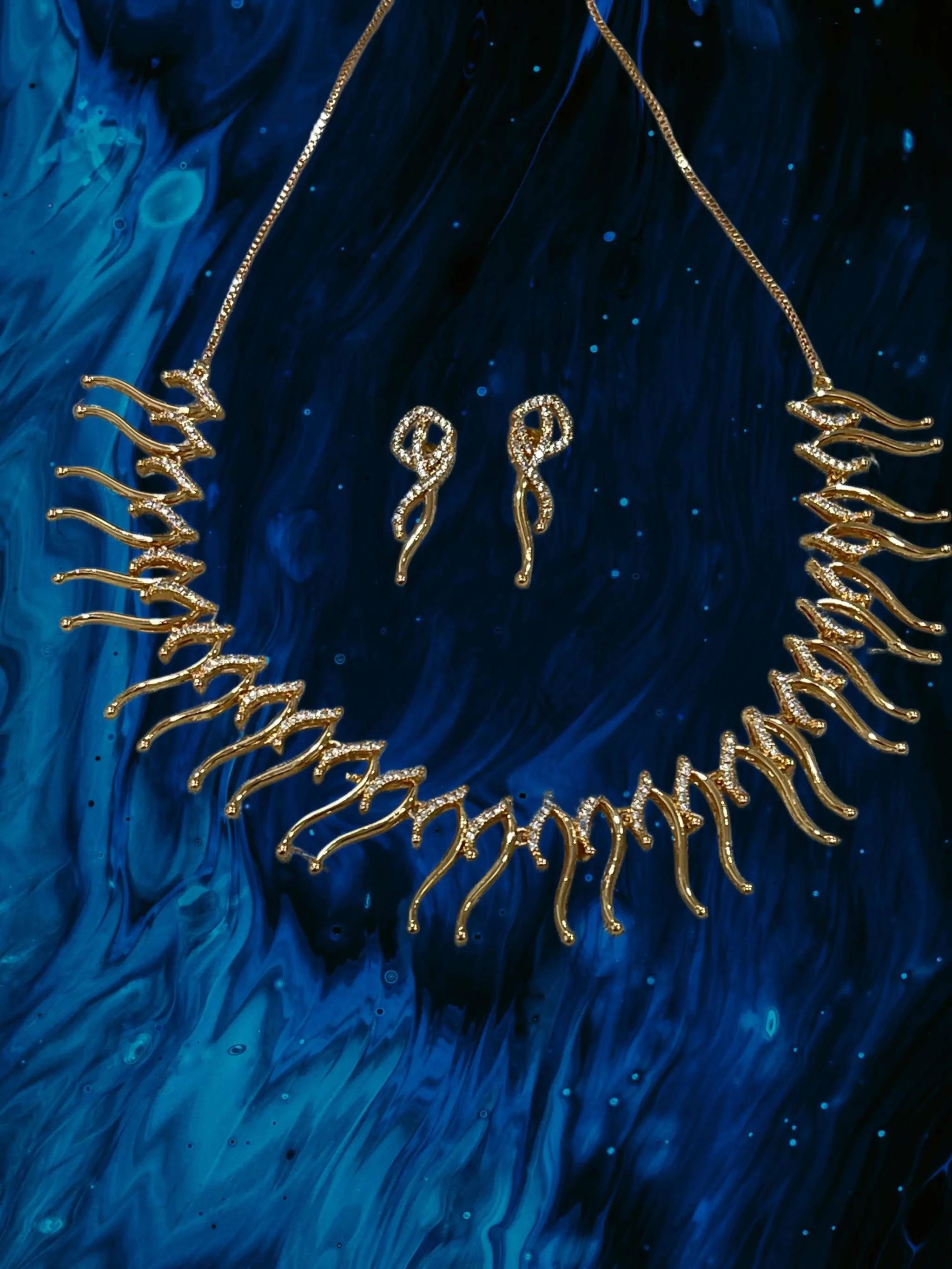 Eclectic Elegance Necklace Set in adjustable rose gold with intricate bold design and matching earrings on blue background